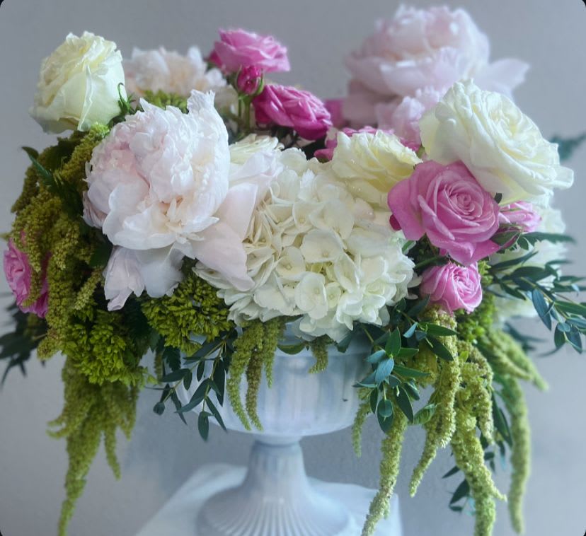 Pink and white roses with hydrangeas in a white pedestal vase