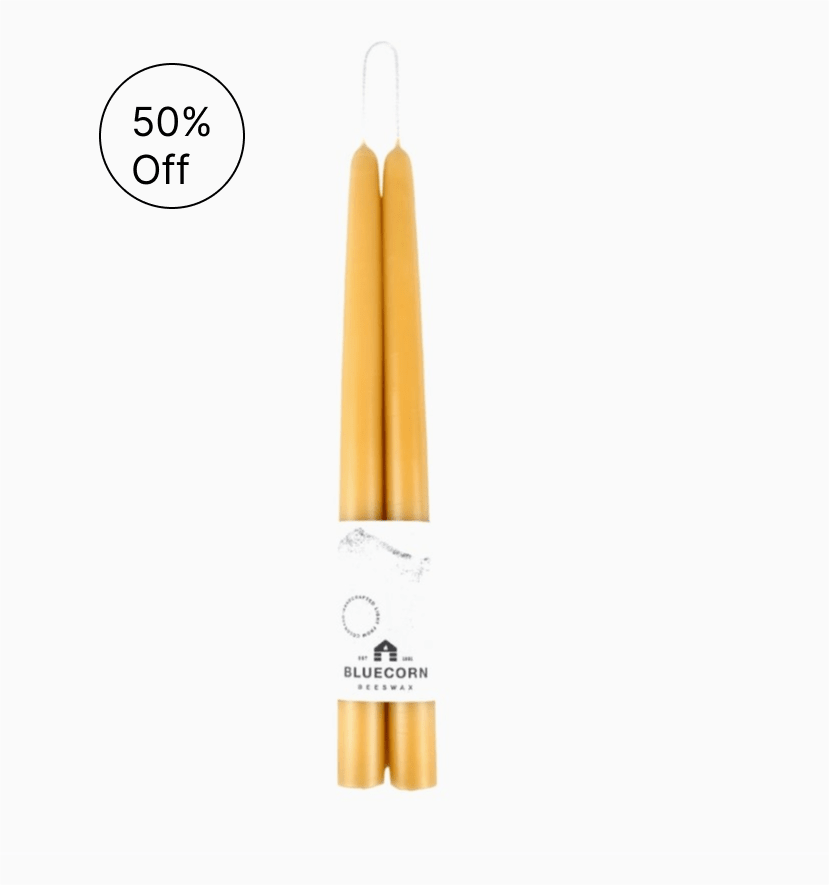 Pair of golden taper candles wrapped together with a white Bluecorn Beeswax label