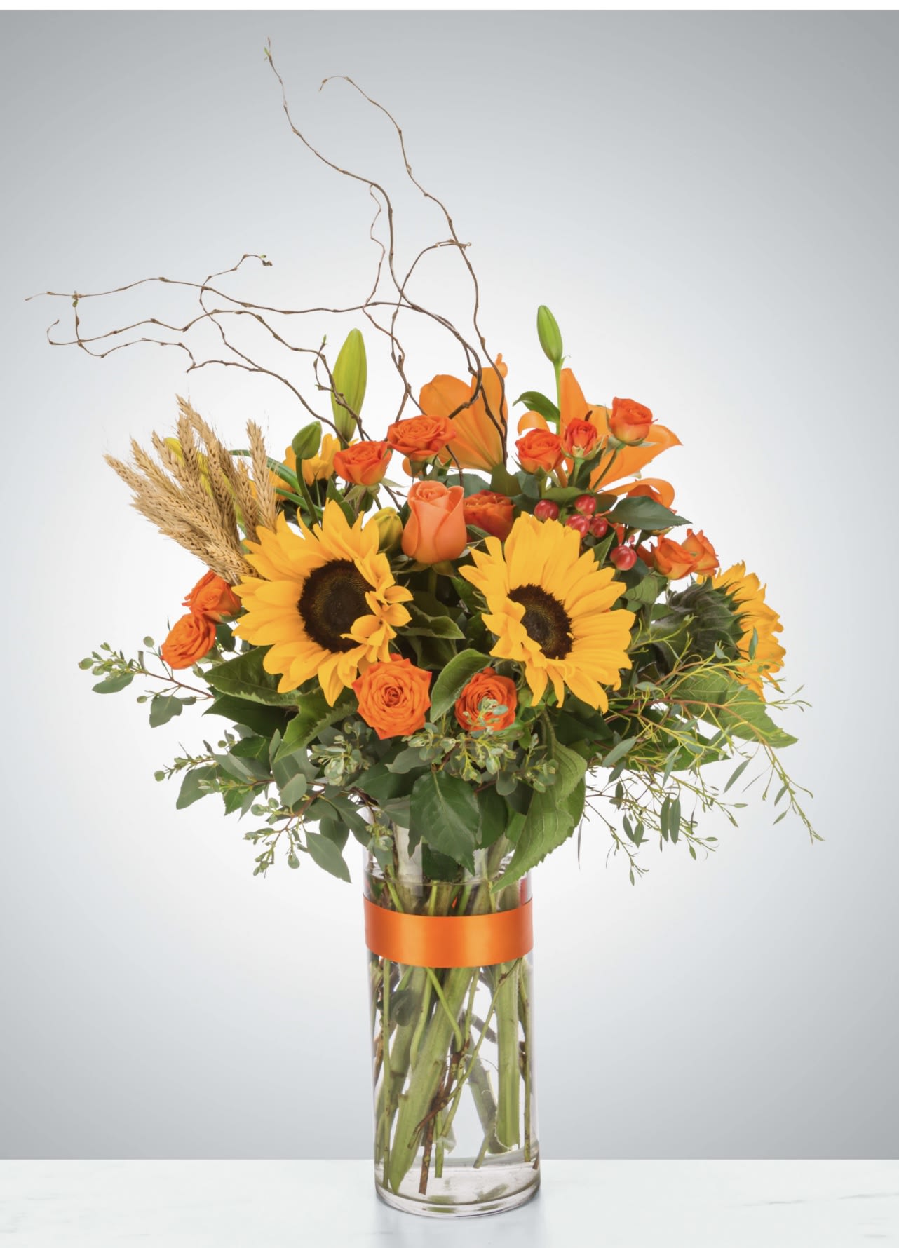 Hayride by BloomNation™ - The ultimate fall flower mix featuring sunflowers and a variety of orange flowers with eucalyptus and curly willow accents. Send this arrangement for Halloween, Thanksgiving, or to celebrate the season!  Approximate Dimensions: 18"D x 29"H
