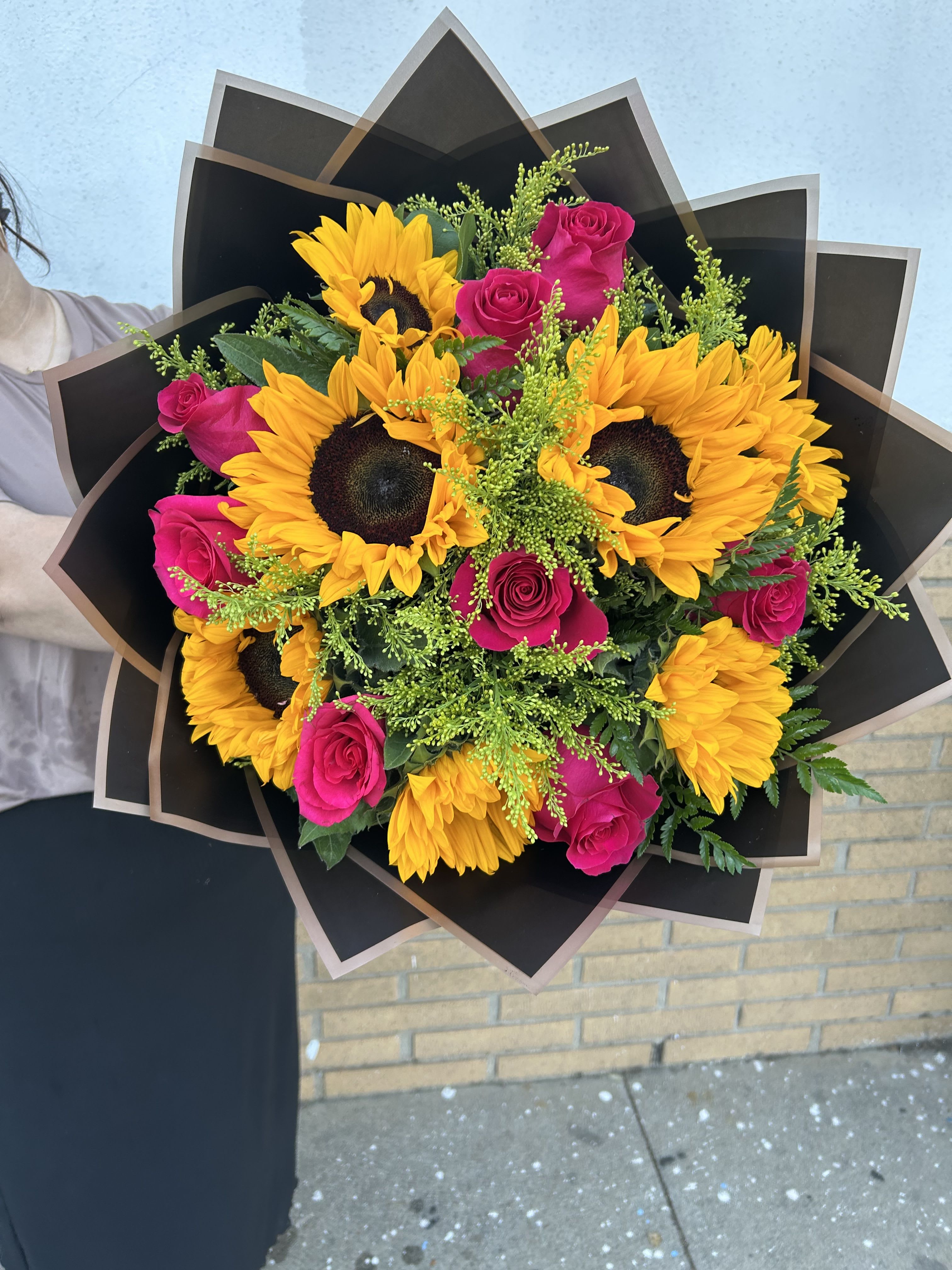 Bouquet of yellow sunflowers and hot pink roses wrapped in black paper