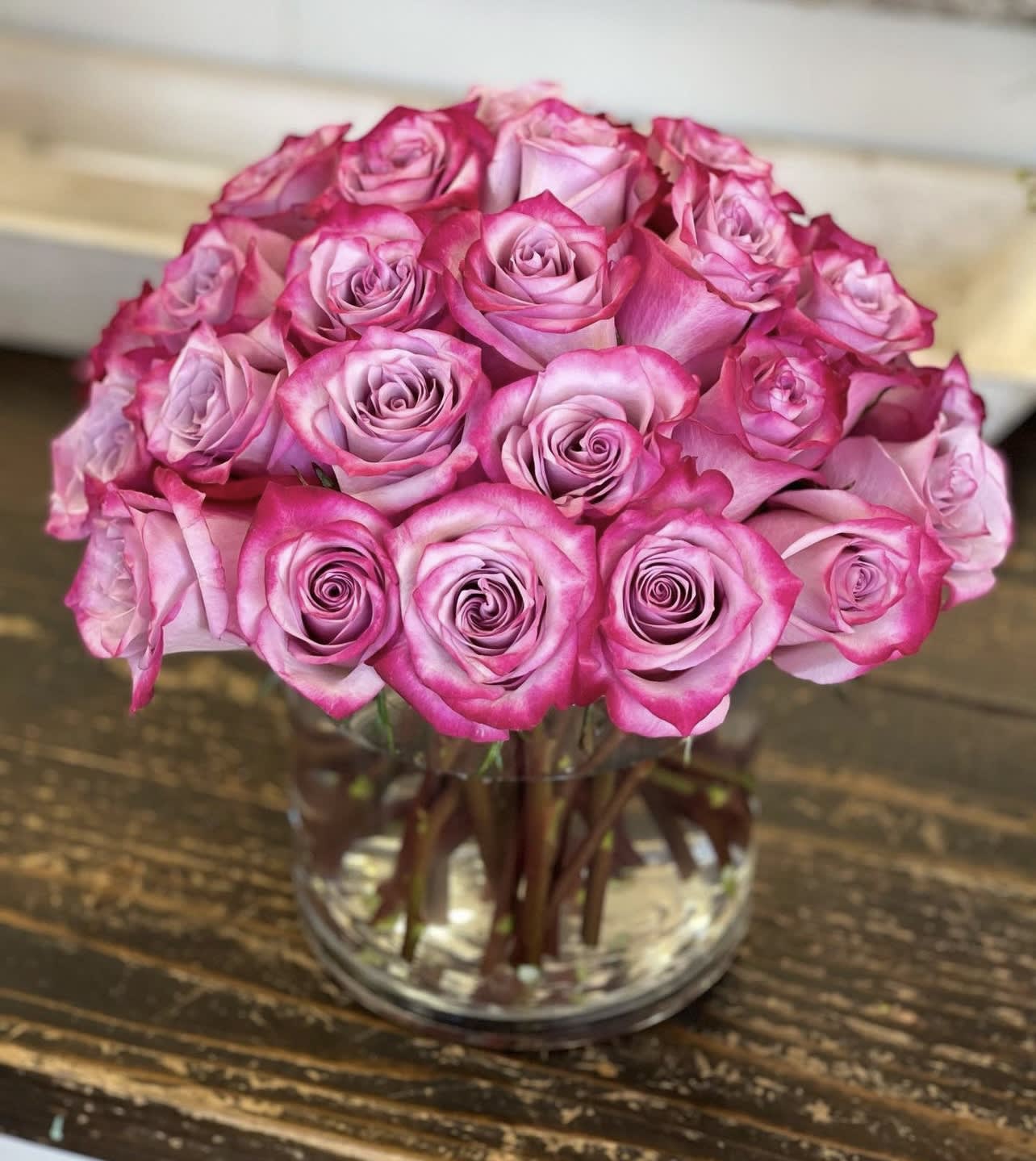 Tightly clustered pink roses arranged in a round dome in a clear glass vase