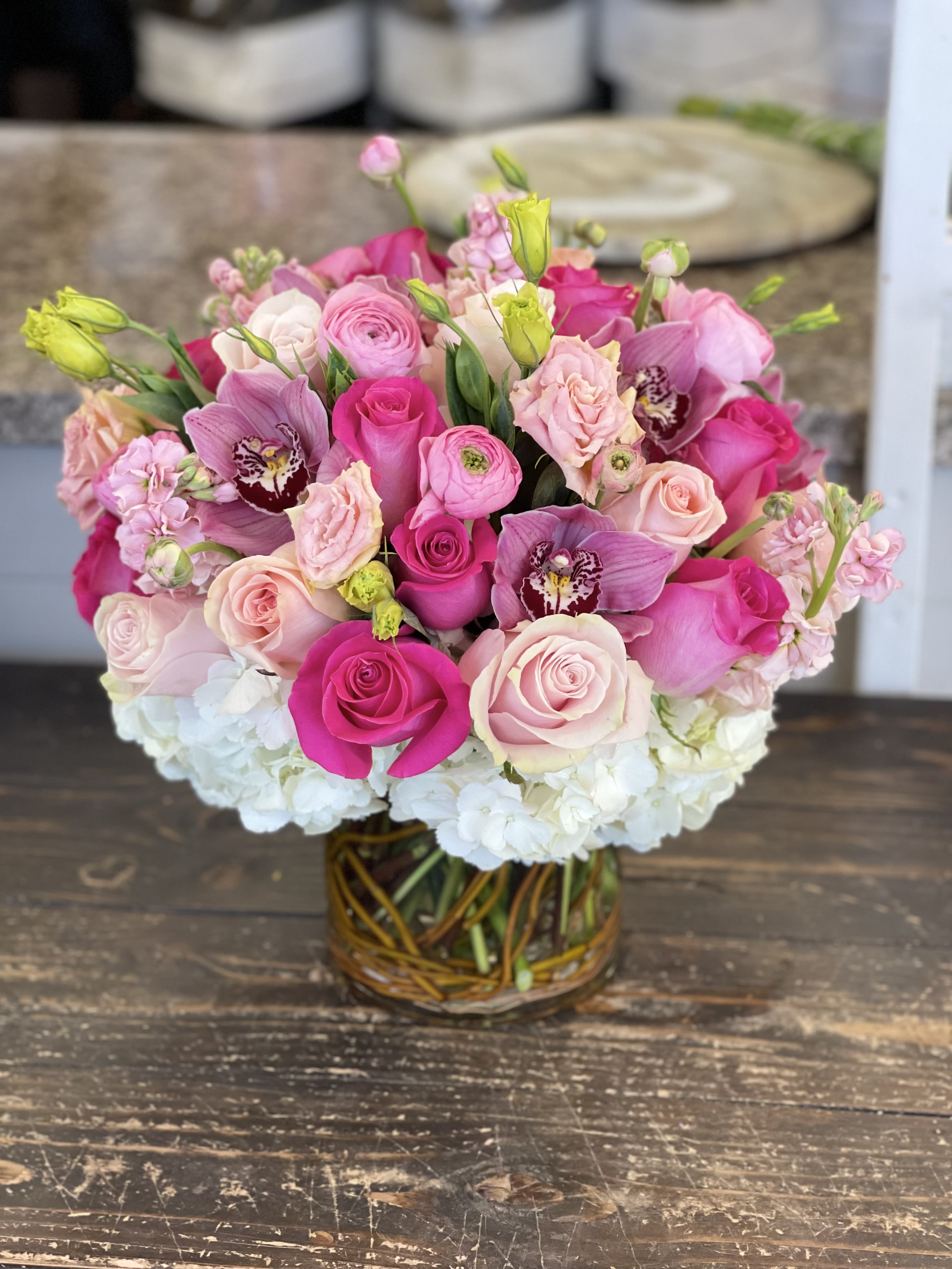 Pink and white rose bouquet with orchids in a glass vase