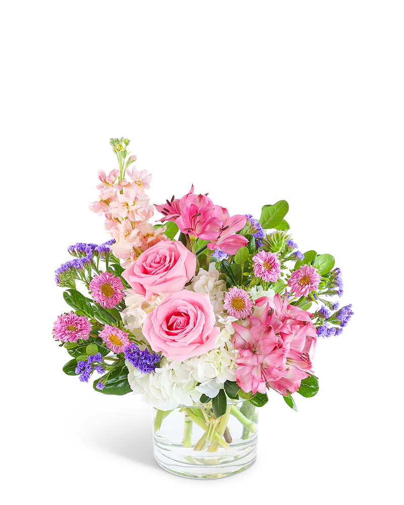 Pink roses and mixed blooms arranged in a clear glass vase