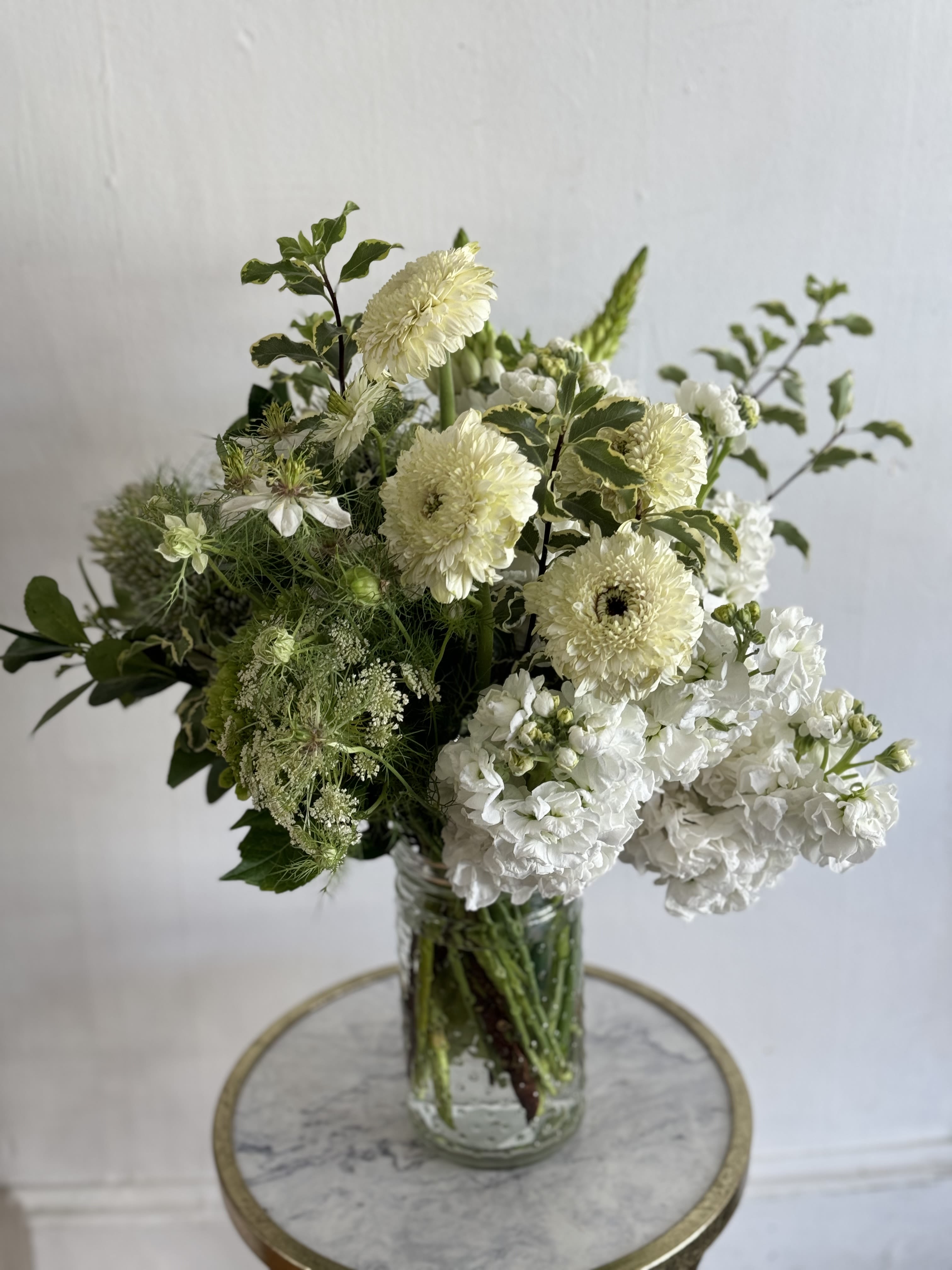 Jar Full of Nuetrals- DESIGNERS CHOICE  - A soft, garden-fresh bouquet in calming neutrals,  a gentle way to say happy birthday, get well, or thank you. The arrangement's restrained palette of white, pale greens and creates an understated elegance that makes the recipient feel soothed and truly seen. Ideal for just-because moments, housewarming, sympathy, or to mark congratulations.DESIGNERS CHOICE   Choose this arrangement when you want to offer comfort, celebrate quietly, or brighten a bedside or entry table; it reads as calm and natural on display. Vase included for easy styling-trim stems and refresh water every 2-3 days for best longevity, and consider placing away from direct heat to preserve the soft, neutral palette.
