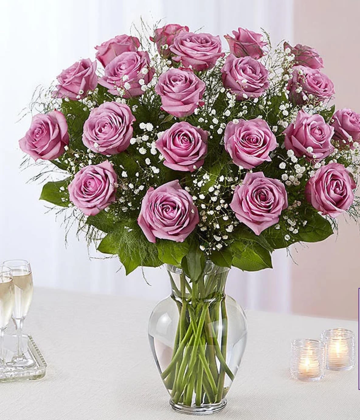 Pink roses arranged in a clear glass vase with baby's breath