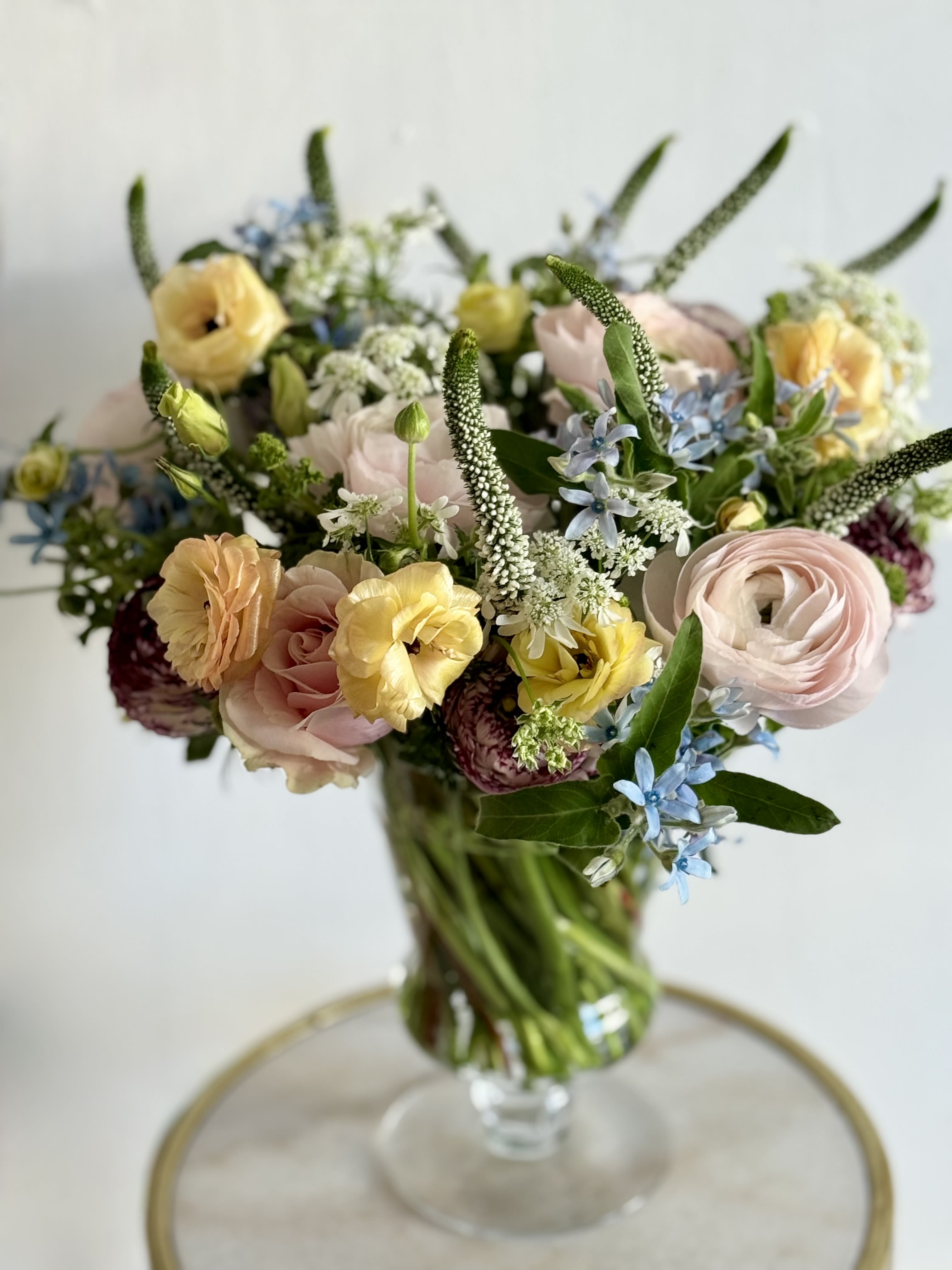 Pastel Compote - Soft pink and buttery yellow blooms mingle with soft pink and white flowers in this pastel compote. A spring-ready flower arrangement perfect for birthdays, thank-yous, or a just-because celebration for someone who loves soft, romantic color. The clear glass vase keeps the look airy and garden-fresh, so the person you're thinking of will feel gently celebrated the moment it arrives.  Arranged low in a compote-like clear glass vase. It arrives ready to display; simple daily water changes and a clean vase will keep the blooms looking fresh through the week.