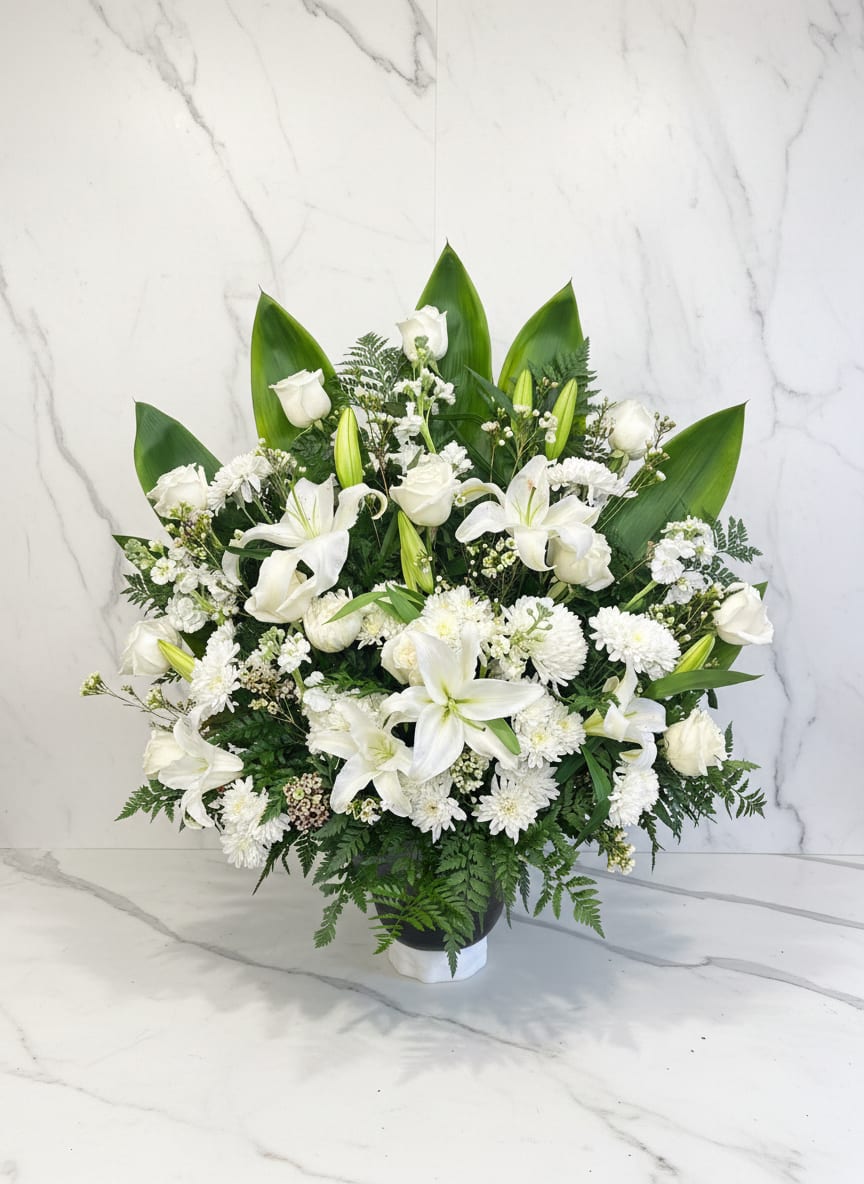 White lilies and roses in a black vase with green foliage