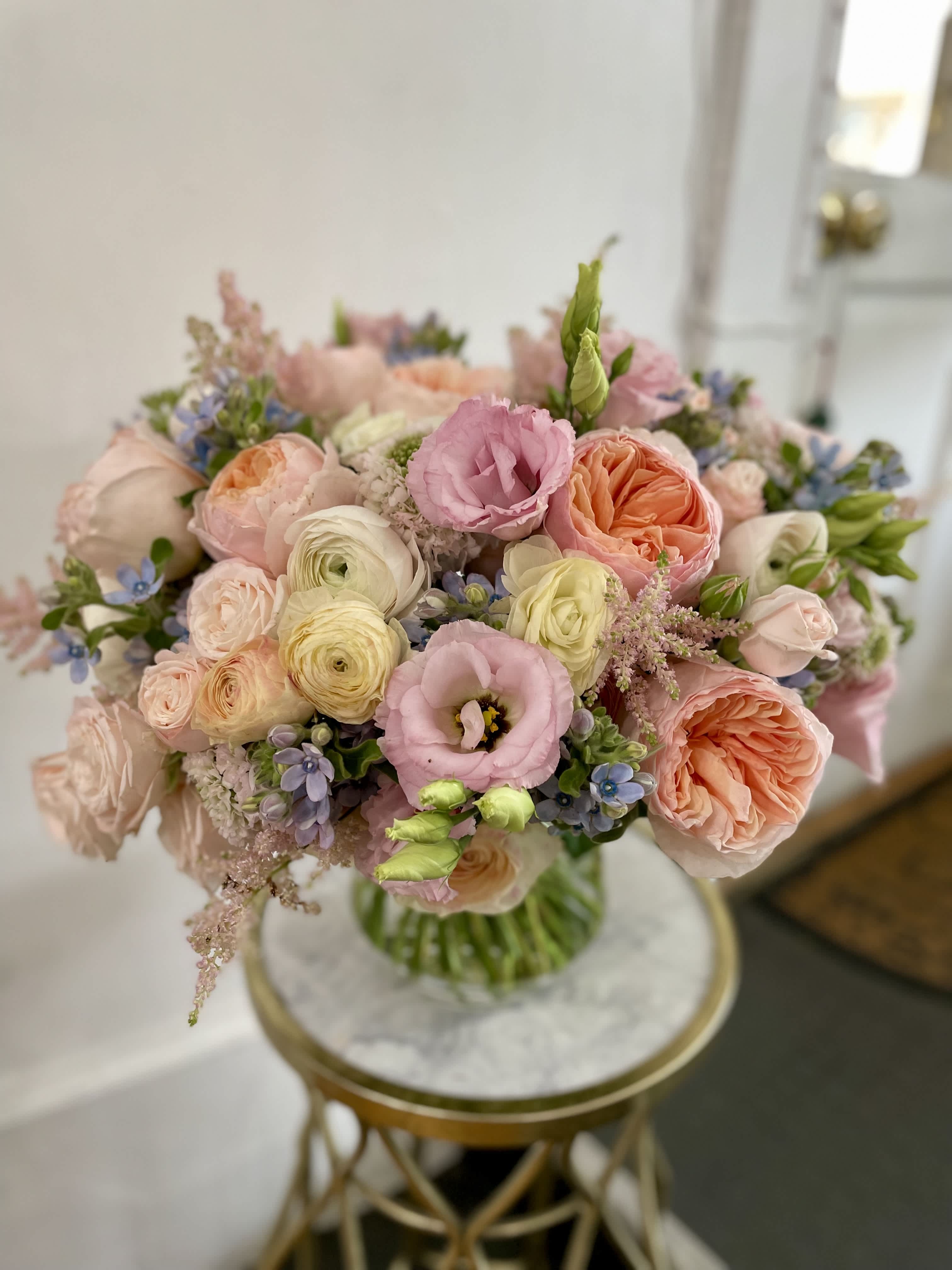 Pastel bouquet of roses, ranunculus, and pink lisianthus in a vase
