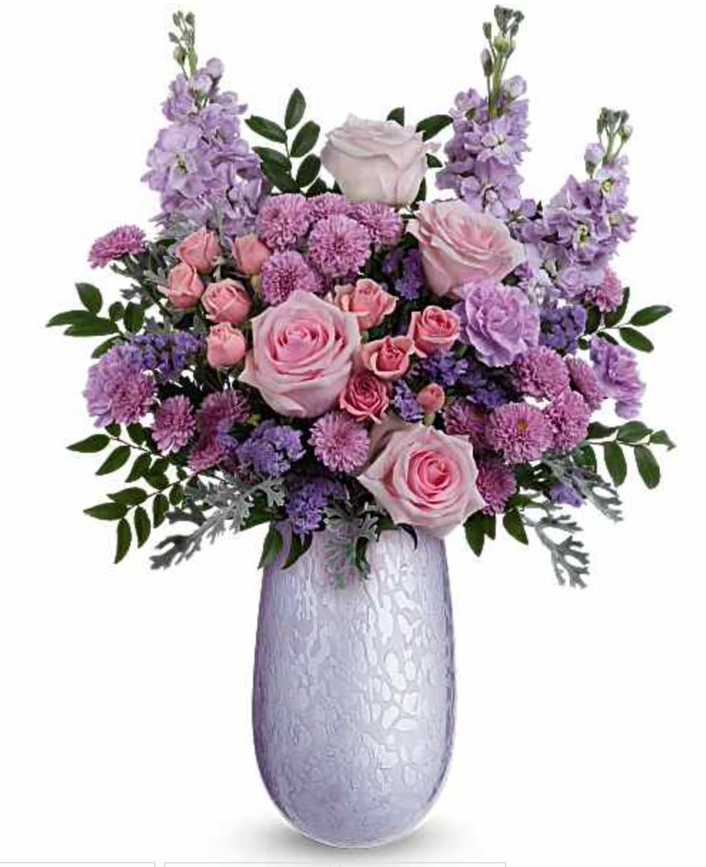 Joyful Blossoms Bouquet - What a treat! Overflowing with pink roses and lavender blooms, this stunning Mother's Day bouquet is artfully arranged in our hand-blown iridescent glass Vivi vase-a keepsake Mom will treasure. The Joyful Blossoms Bouquet features pink roses, pink spray roses, lavender carnations, lavender stock, lavender button spray chrysanthemums, lavender sinuata statice, silver lace dusty miller, and huckleberry. Arranged in our hand-blown iridescent Vivi vase, this elegant bouquet is a perfect Mother's Day gift. Orientation: All-Around  SUBSTITUTION POLICY – Always deliver the freshest flowers! Please note the bouquet pictured reflects our original design.  If the exact flowers or container in this arrangement are not available, our local florists will create a beautiful bouquet with the freshest available flowers.