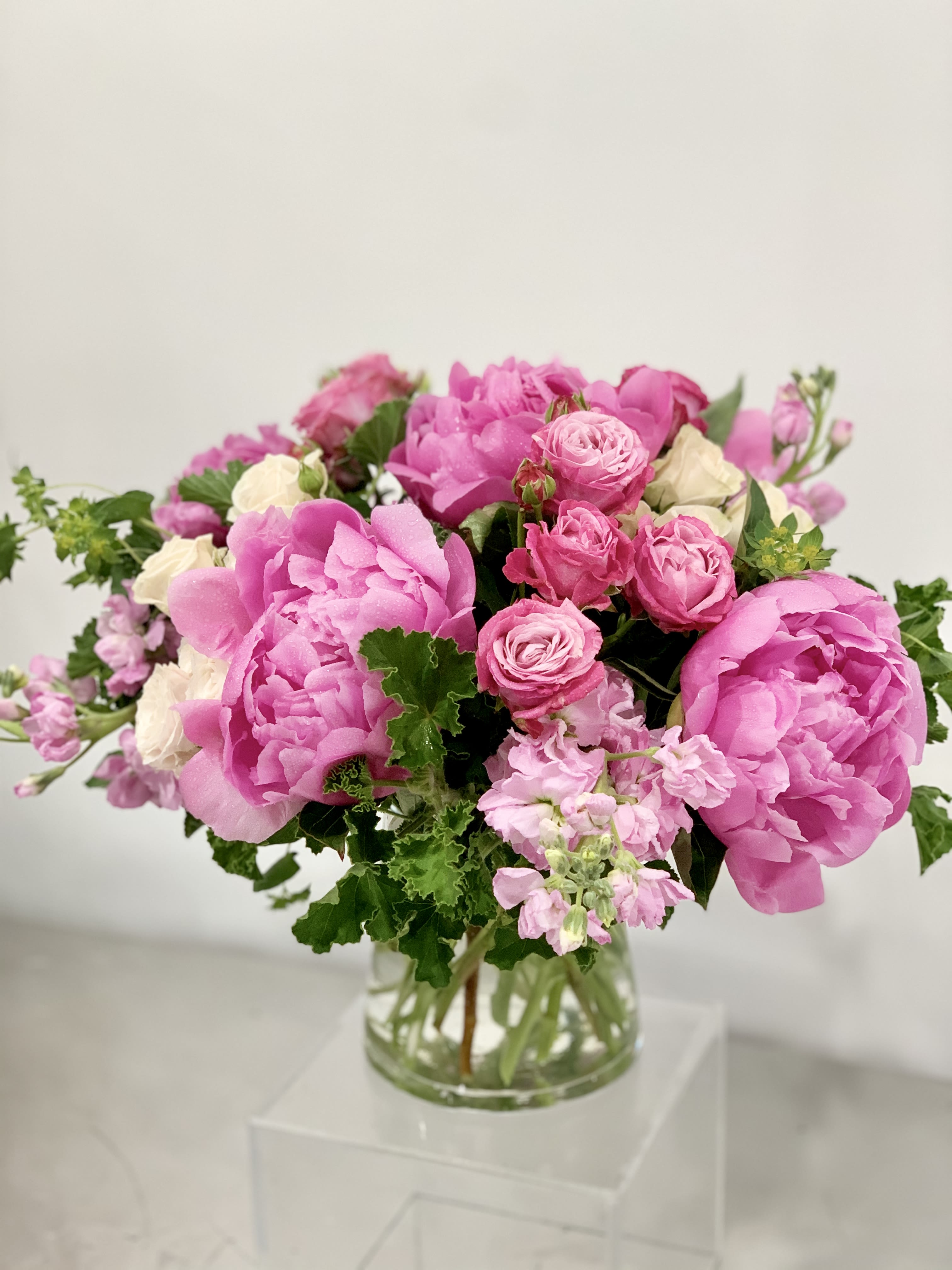 Pink peonies and roses arranged in a clear glass vase