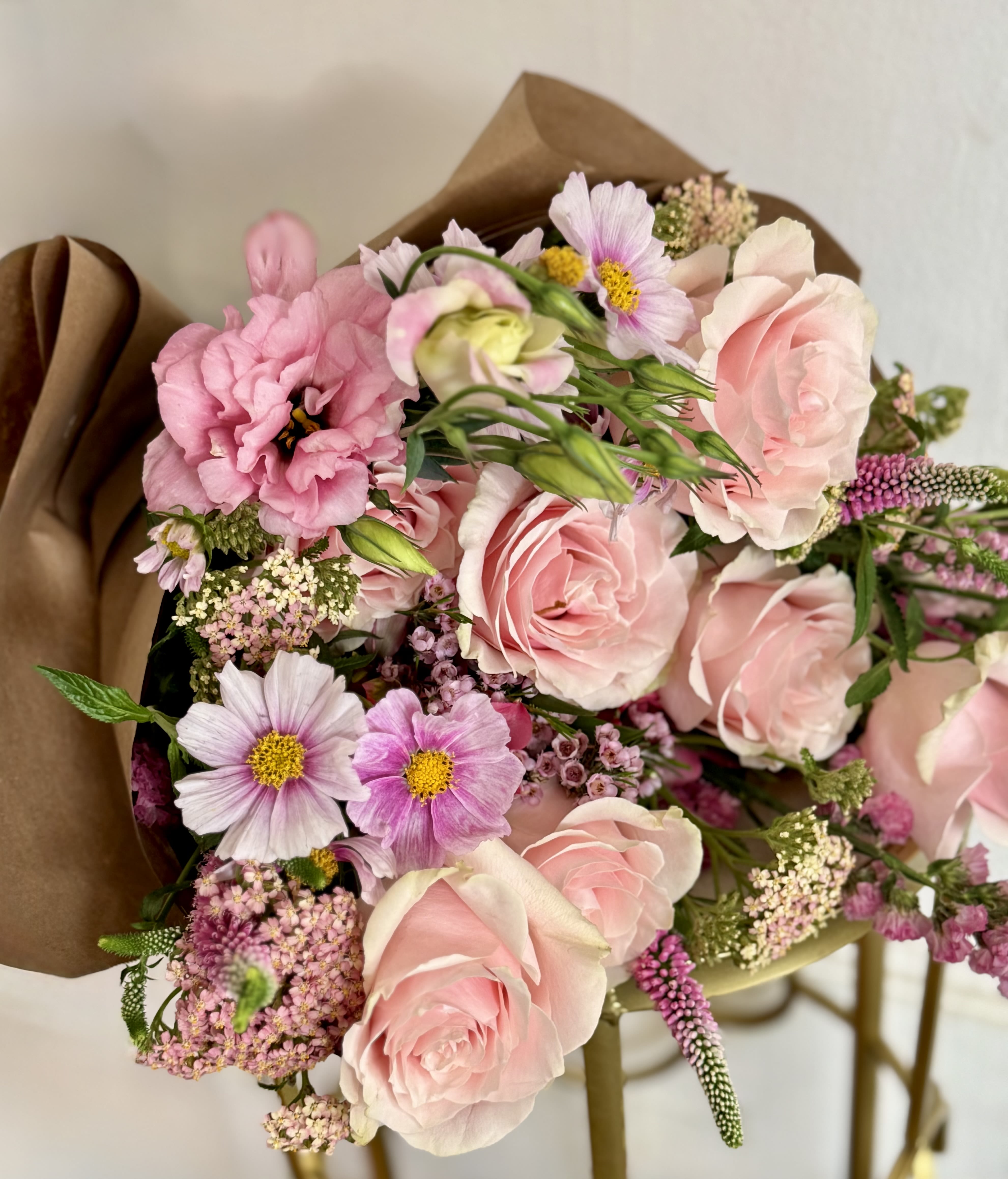 All the Pinks - DESIGNERS CHOICE  - The gentle mix of pinks, and fresh green foliage gives the arrangement an airy, romantic feel that will make the person you're thinking of feel truly seen and cherished. Hand-tied bouquet. Paper wrapped. Designers Choice   This generous arrangement layers pink and green. Sized to read abundant and garden-fresh, it arrives loose and tactile - simple care (fresh water and occasional stem trims) keeps the blooms looking their best. Orders are designer's choice to guarantee the freshest premium flowers for Mother's Day, funerals, thank-you gestures, or everyday celebrations. 