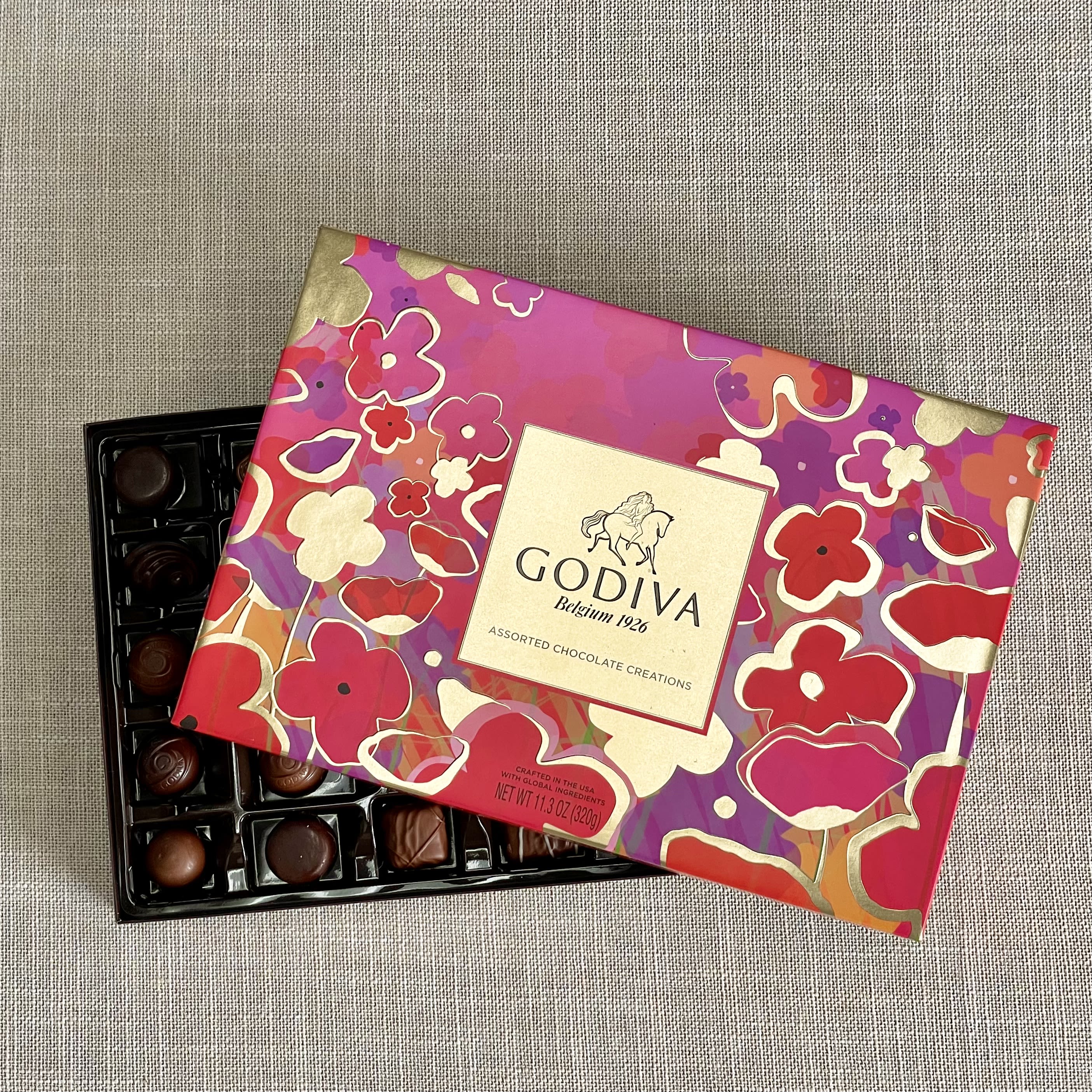 Box of assorted chocolates with a colorful floral lid