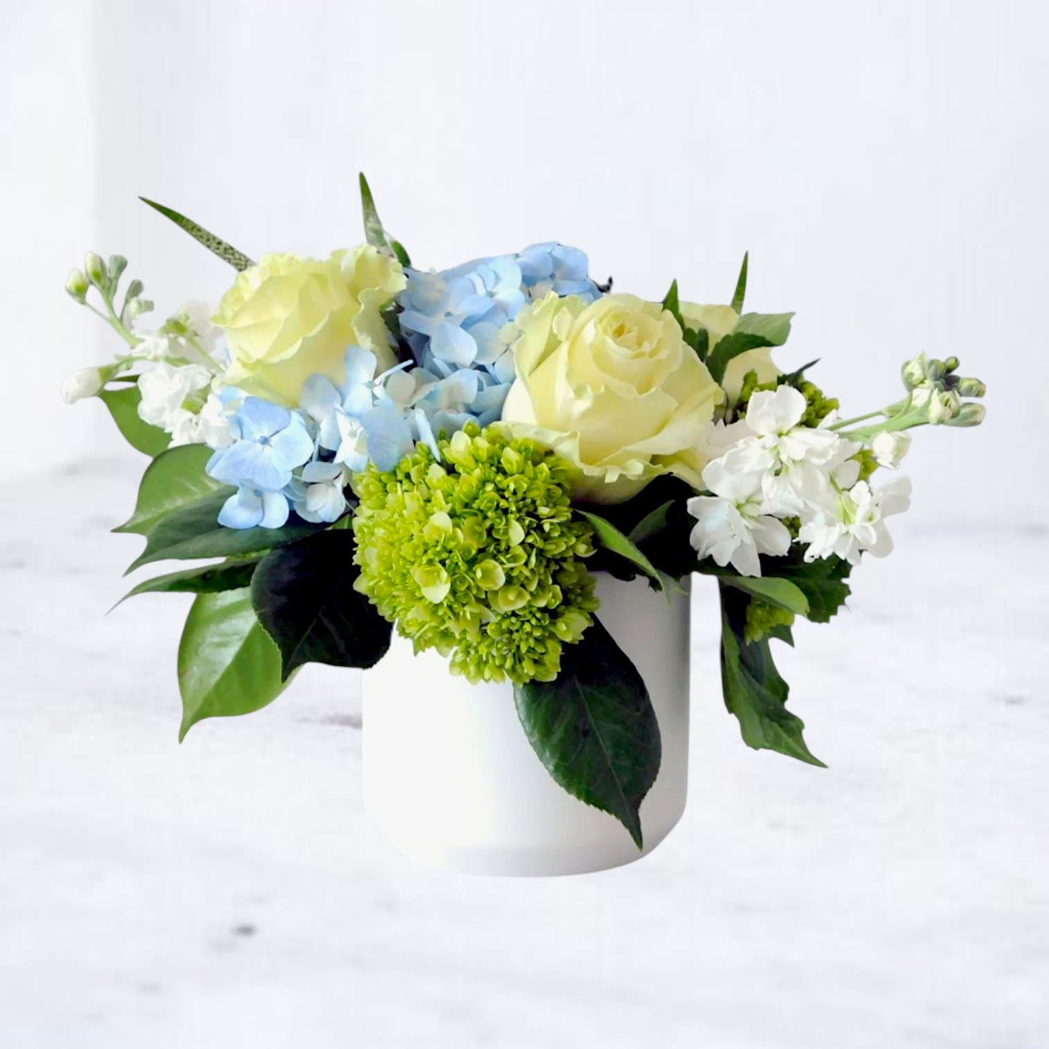 Quiet Current - Send a thoughtful expression with Quiet Current, a soft and calming flower arrangement designed in shades of blue, white, and fresh green. Featuring premium blooms like hydrangea, roses, lisianthus, and seasonal florals, this garden-inspired design offers a peaceful and elegant way to send sympathy flowers, condolences, or thoughtful support.  Handcrafted by a local florist and available for same-day flower delivery in Magnolia, TX and surrounding areas including The Woodlands, Montgomery, Conroe, Spring, and Tomball, this arrangement is ideal for sympathy deliveries to homes, hospitals, funeral services, or memorial gatherings. Its clean, modern style and soothing color palette create a meaningful gesture that feels refined, comforting, and beautifully understated.  Whether you're sending sympathy flowers, comfort flowers, or a graceful arrangement to brighten someone’s day, Quiet Current is designed with fresh seasonal blooms and an airy, natural style that feels timeless and sincere.