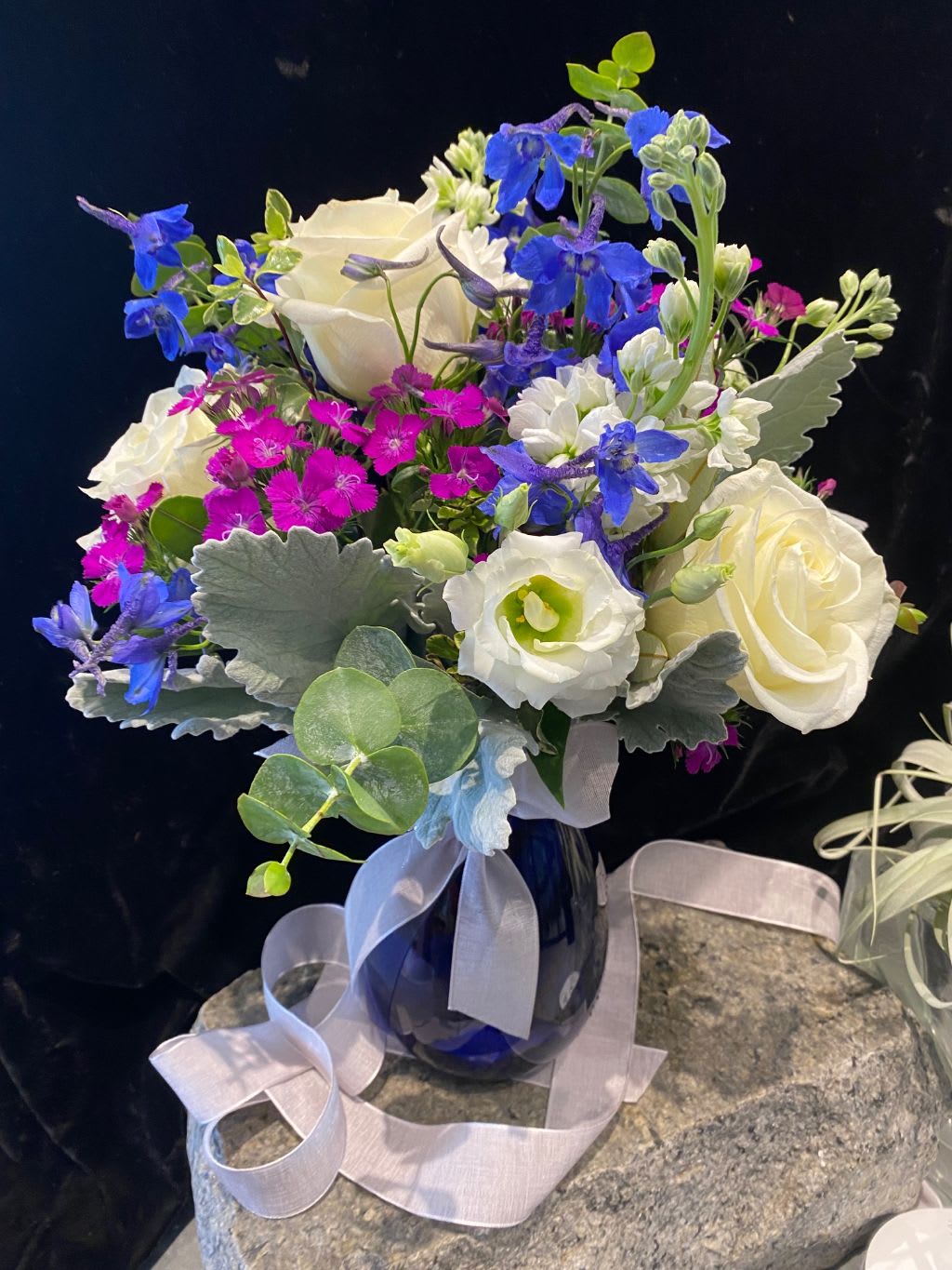 Bouquet of white roses, blue flowers, and pink dianthus in a blue vase