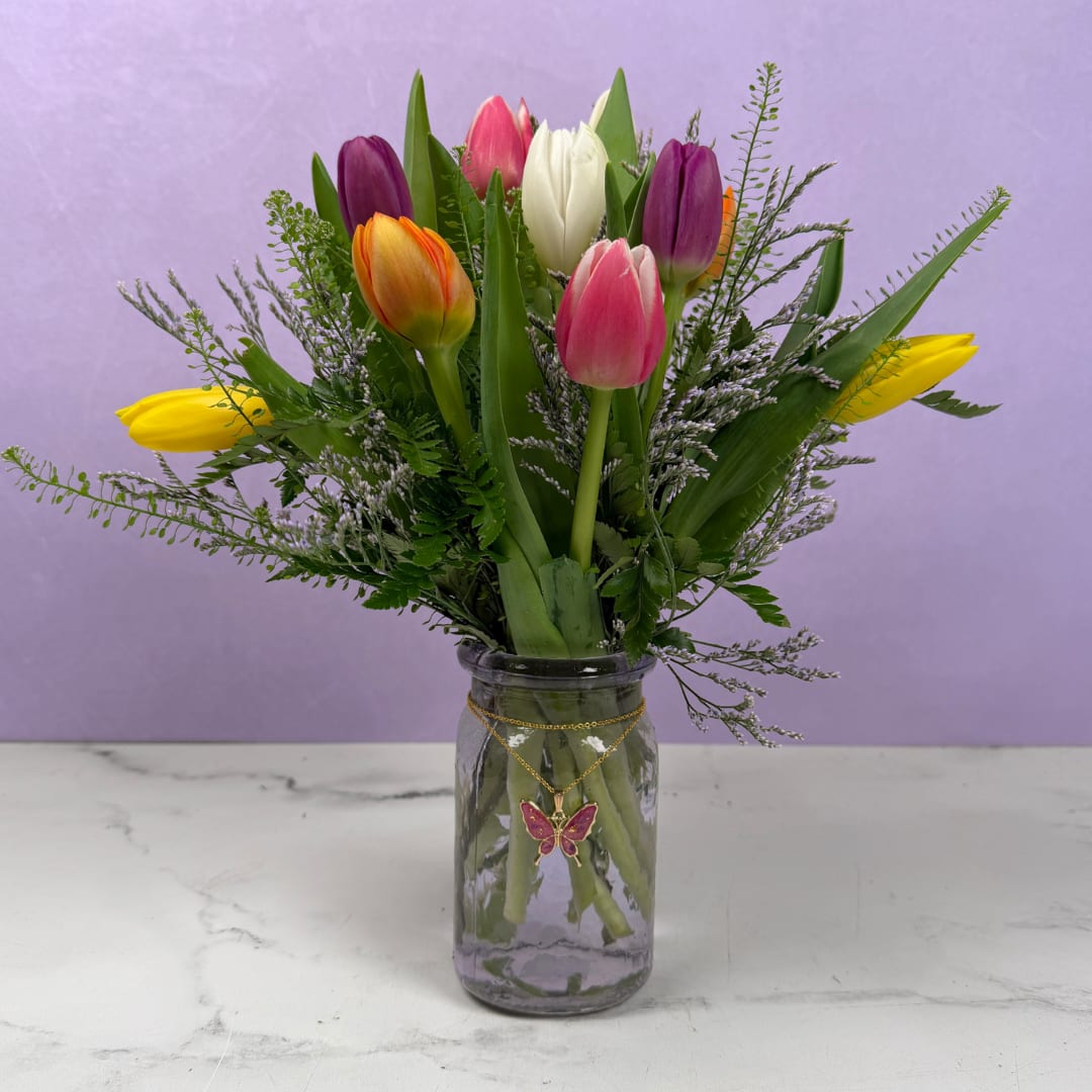 Butterfly Blossoms - Vibrant, colorful tulips are joined with airy filler flowers in this Butterfly Blossoms flower arrangement, a darling spring bouquet perfect for Mother's Day, an anniversary, or a "just because" surprise. The bright, refreshing composition also works beautifully as a pick-me-up or thinking-of-you gift.  Blooms are gathered in a translucent lavender glass jar, with a delicate, handmade gold butterfly pendant necklace filled with our own pressed flowers created by local artisan Sunshine Orchard Designs draped around the jar's neck, adding a keepsake touch the recipient can wear and treasure. Sized for tabletops and desks, this arrangement brings stunning color and sweet texture to small spaces and arrives ready to display with stems trimmed and water-balanced.