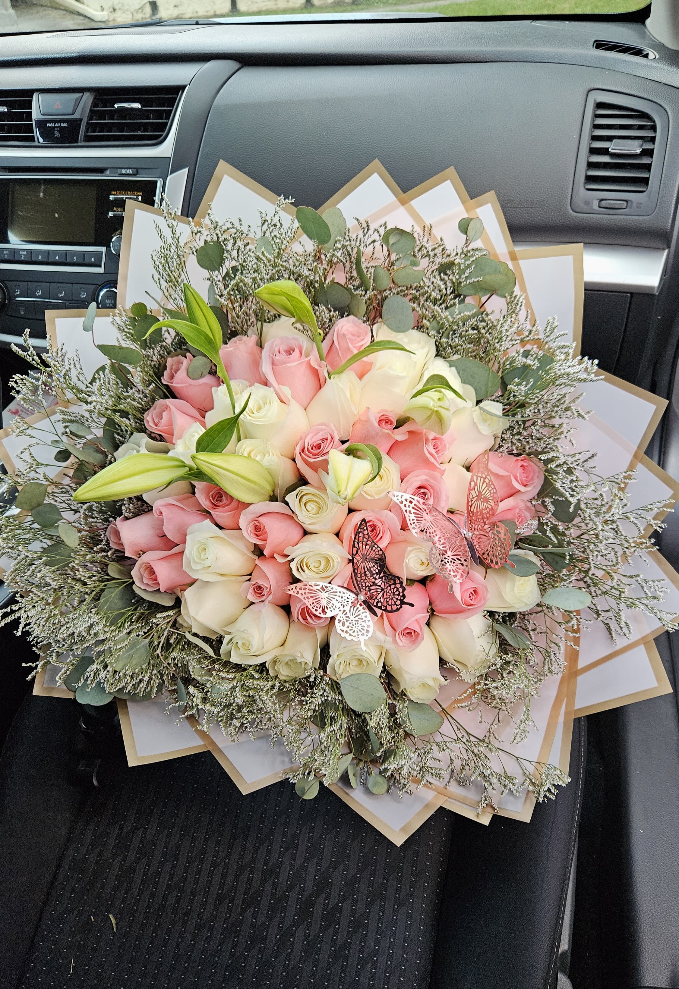 Bouquet of pink and white roses with lilies and butterfly accents