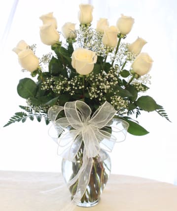 Cream rose bouquet in a glass vase with a sheer ribbon bow