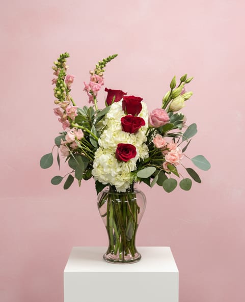 Red roses and white hydrangeas in a clear glass vase
