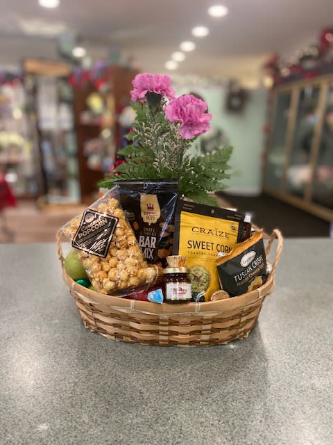 Gift basket with snacks and pink flowers in a woven basket