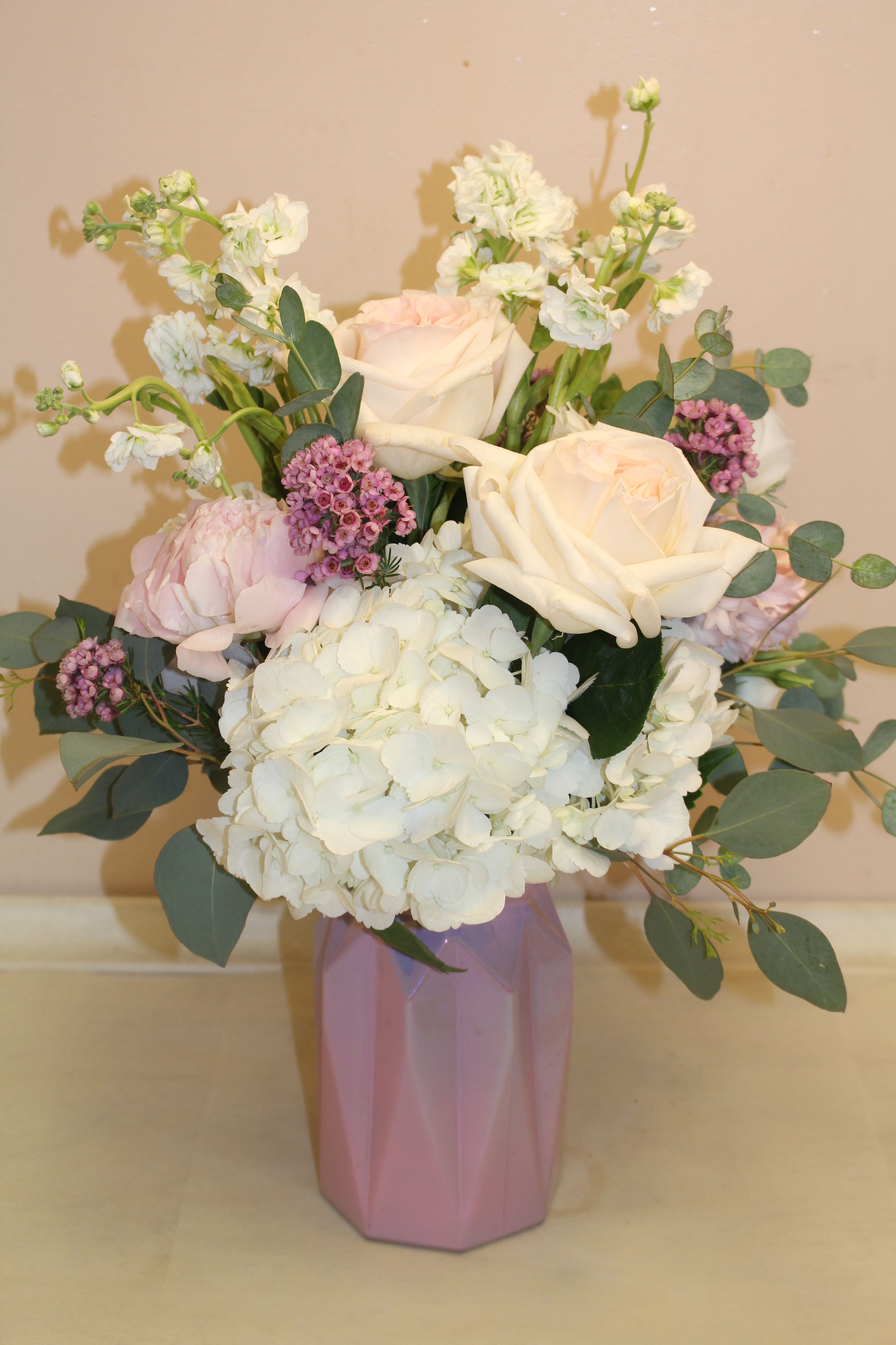Bouquet of white and blush roses with hydrangea in a pink vase