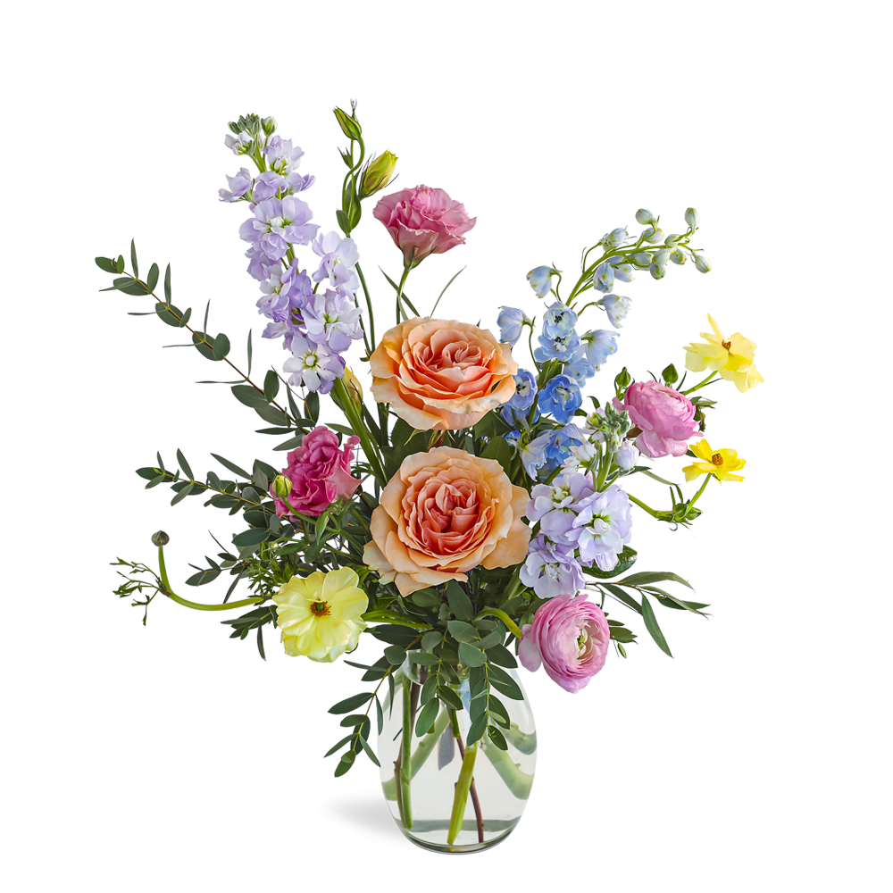 Mixed bouquet with peach roses and pastel flowers in a clear glass vase