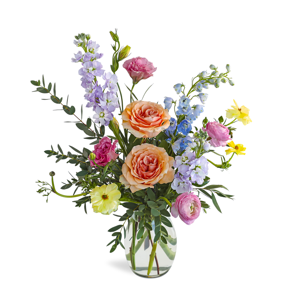 Mixed pastel flower arrangement with peach roses and assorted blooms in a clear glass vase