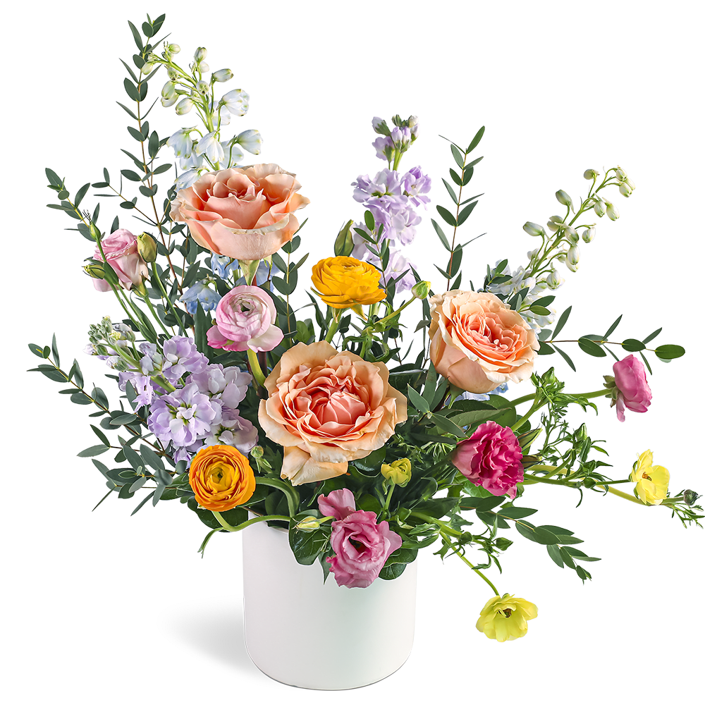 Peach roses and colorful ranunculus with pastel blooms in a white cylinder vase