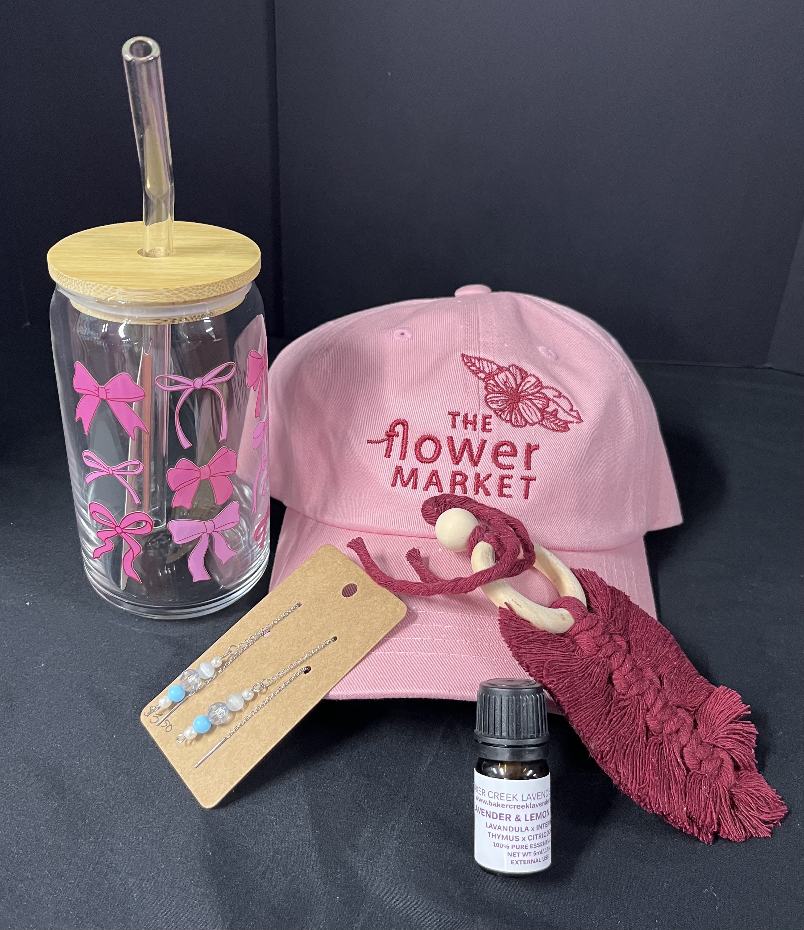 Pink flower market cap with a clear tumbler, earrings, tassel keychain, and small bottle