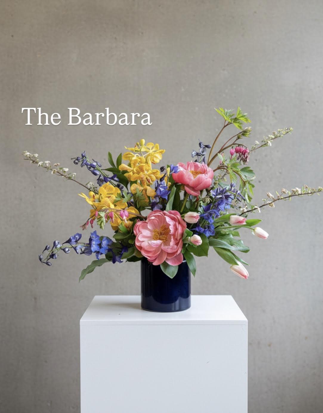 Colorful mixed bouquet in a dark vase on a white pedestal