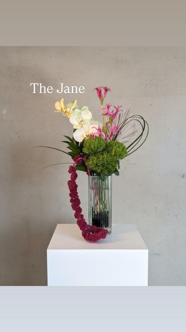 Tall floral arrangement in a clear glass vase with pink, white, and green blooms