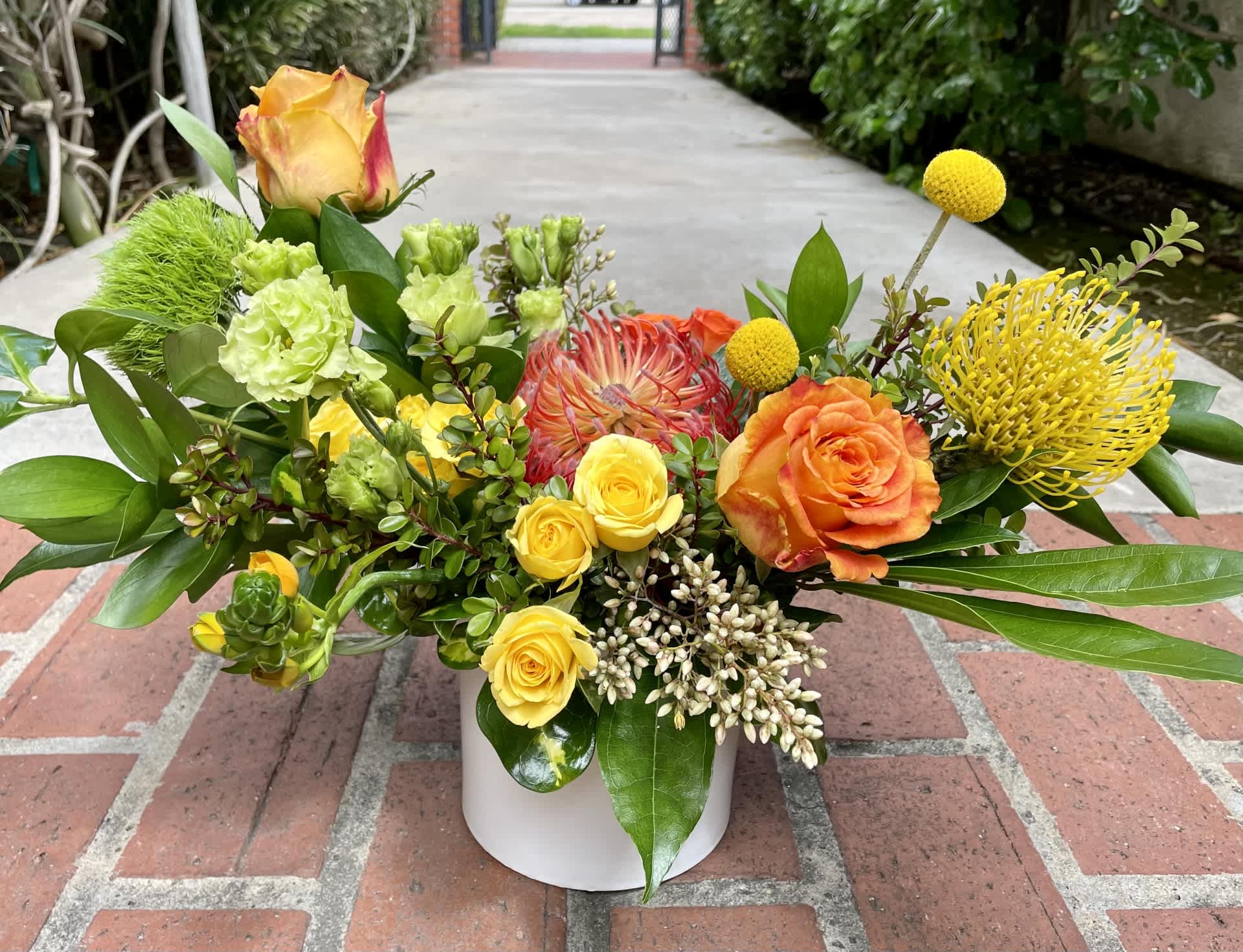 Colorful mixed flower arrangement in a white vase with roses and tropical blooms