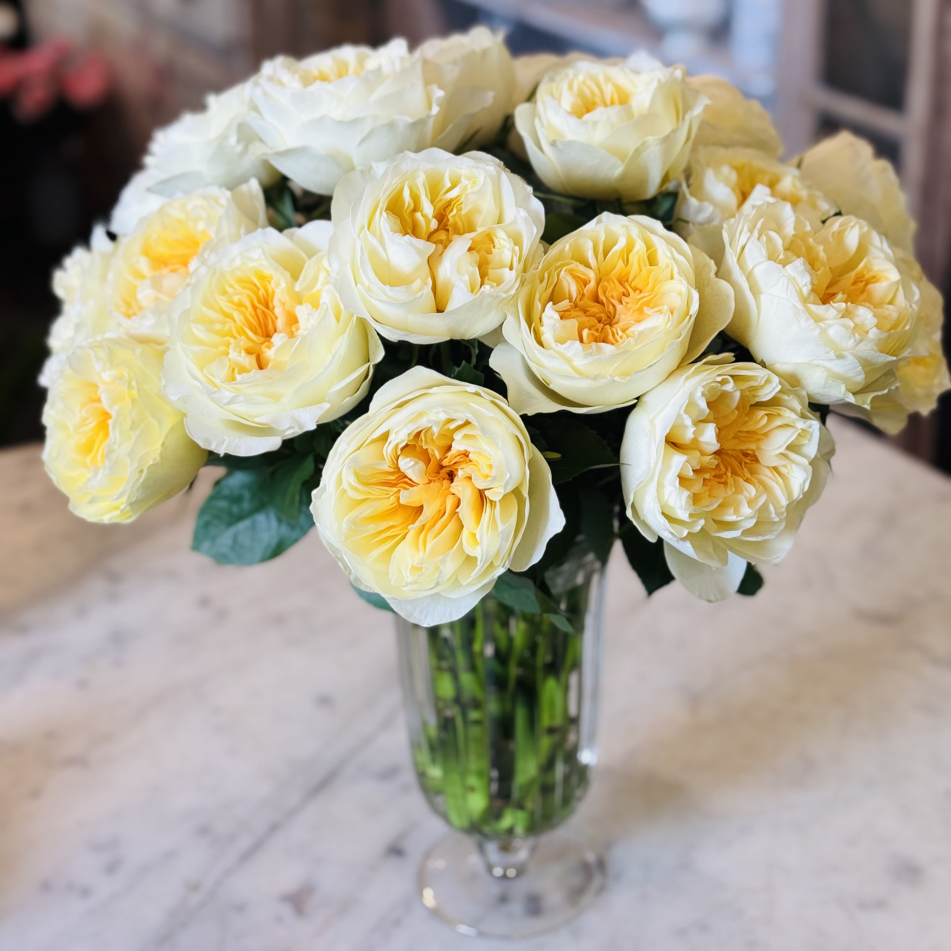 Urban Gardener Lemoncello  - Two dozen Antonia Garden roses loosely arranged in a footed glass urn.