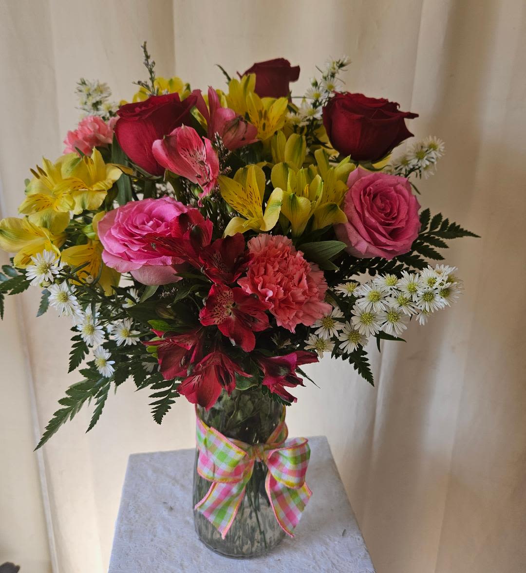 Cherished Moments - Celebrate Mom with a heartfelt gift designed to brighten her day. Cherished Moments is a traditional medium-sized arrangement featuring a beautiful blend of classic blooms in loving, cheerful colors. Elegant red and pink roses symbolize love and appreciation, while soft pink carnations add a touch of warmth and admiration. Bright yellow and red alstroemeria bring vibrant color, complemented by delicate white asters and airy misty blue filler for added texture and charm.  Arranged with lush leather leaf fern greenery, this bouquet offers a full, balanced look that feels timeless and thoughtful. Whether delivered as a surprise or presented in person, Cherished Moments is a lovely way to honor Mom and create memories she'll treasure this Mother’s Day.