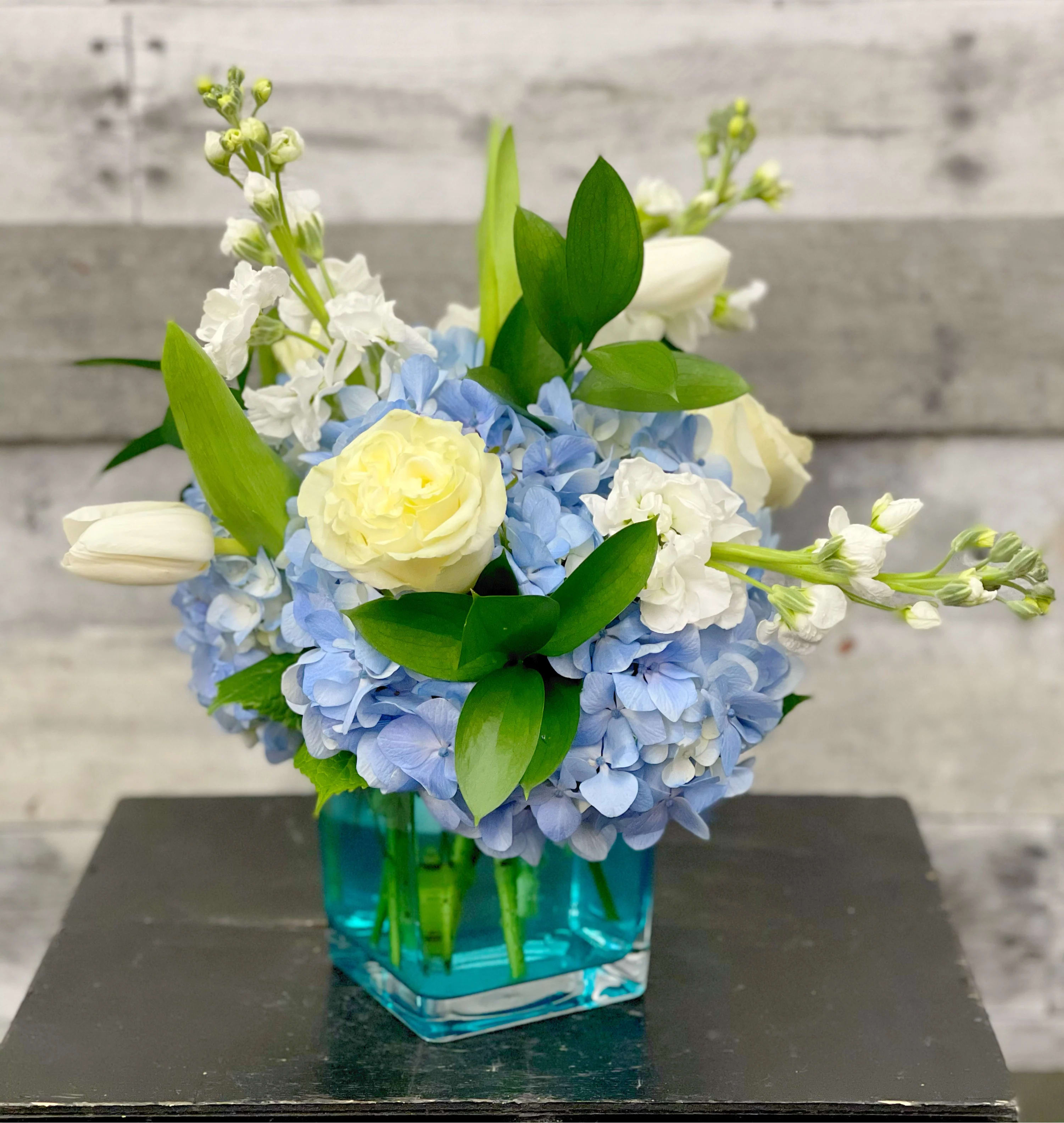 Blue hydrangea bouquet with white roses in a blue glass vase