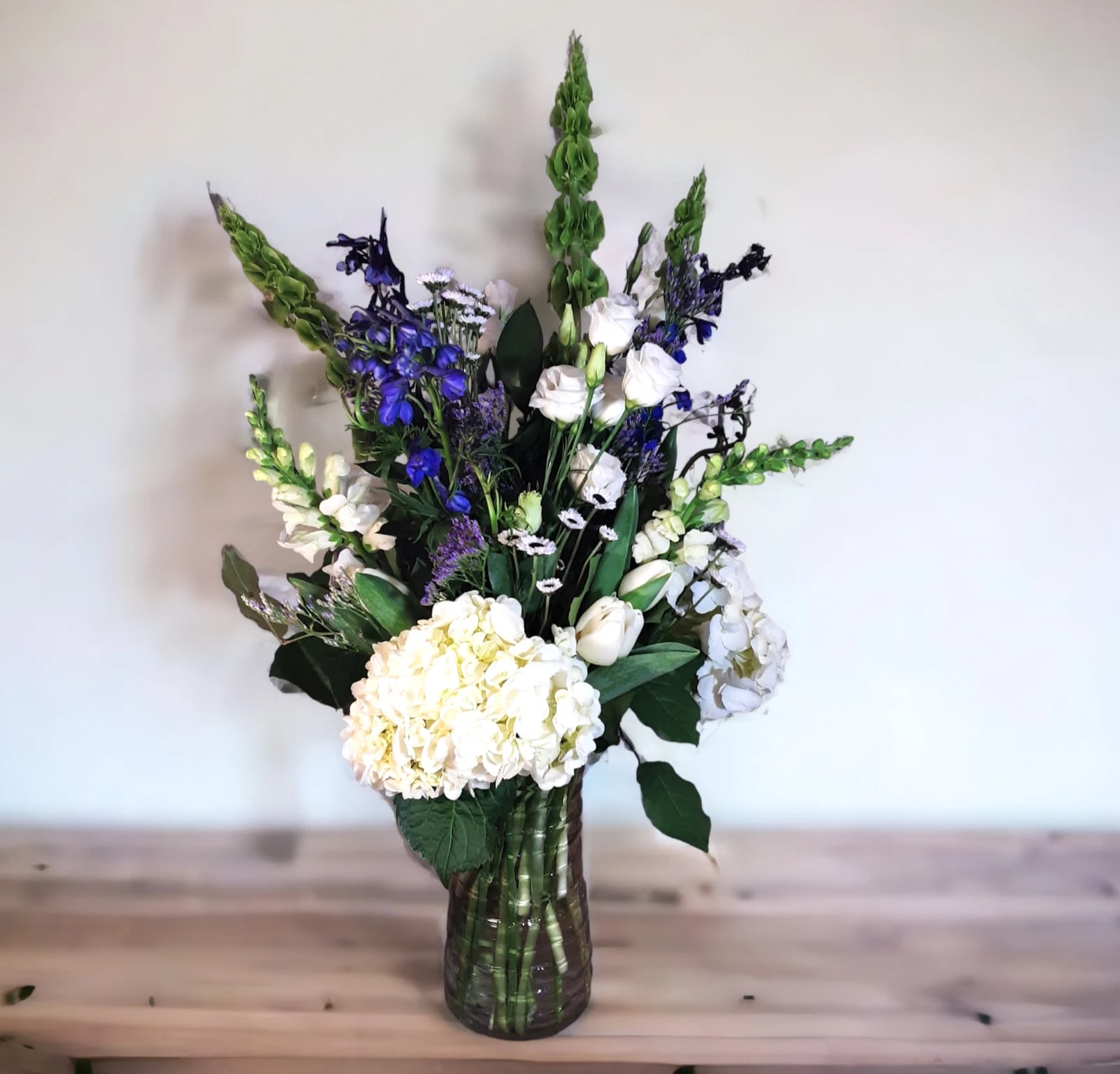 White and blue floral arrangement in a glass vase