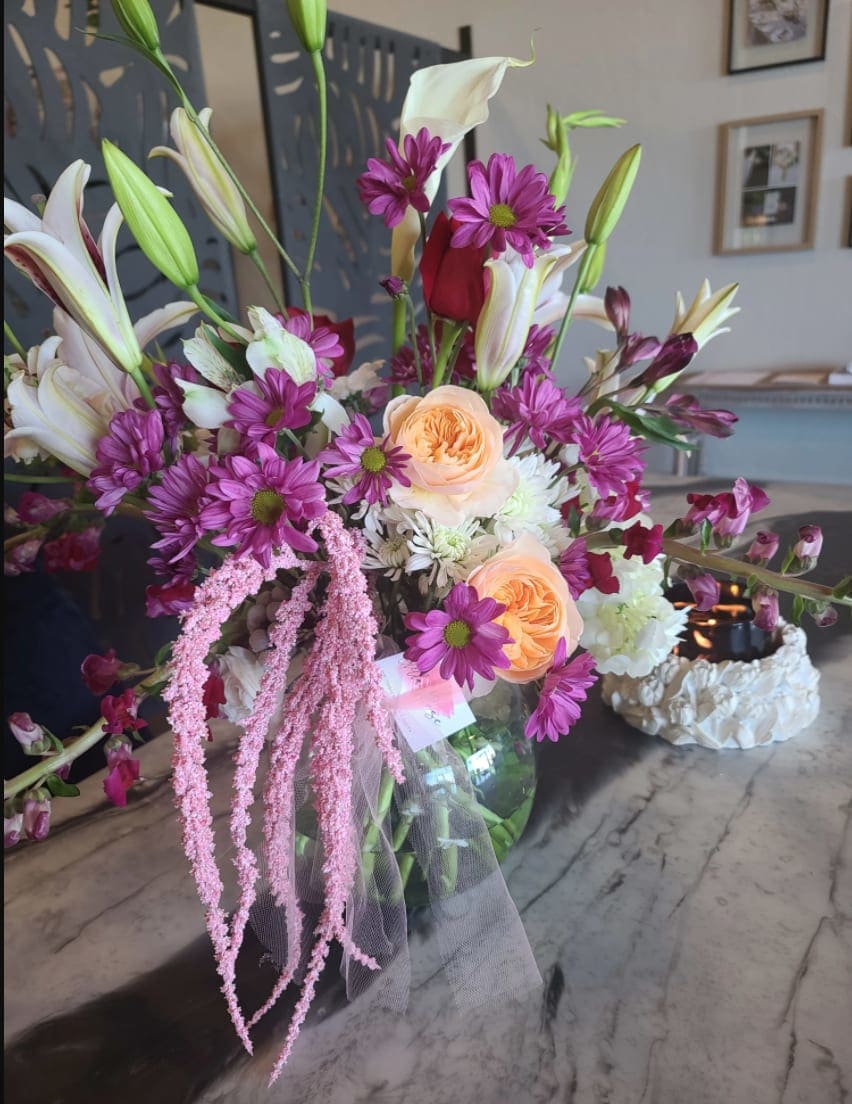 Mixed bouquet with lilies, roses, and purple daisies in a glass vase