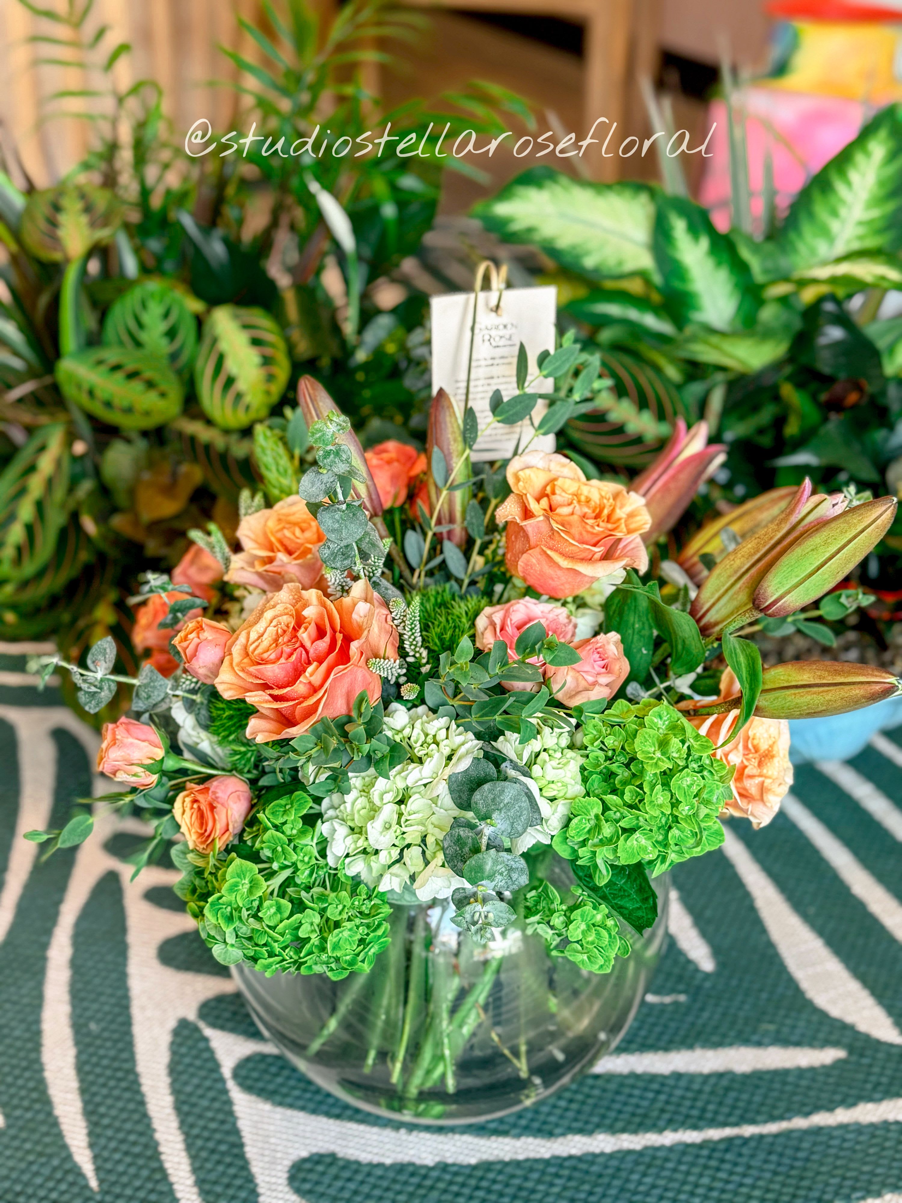 Peach roses and green hydrangeas in a clear glass vase