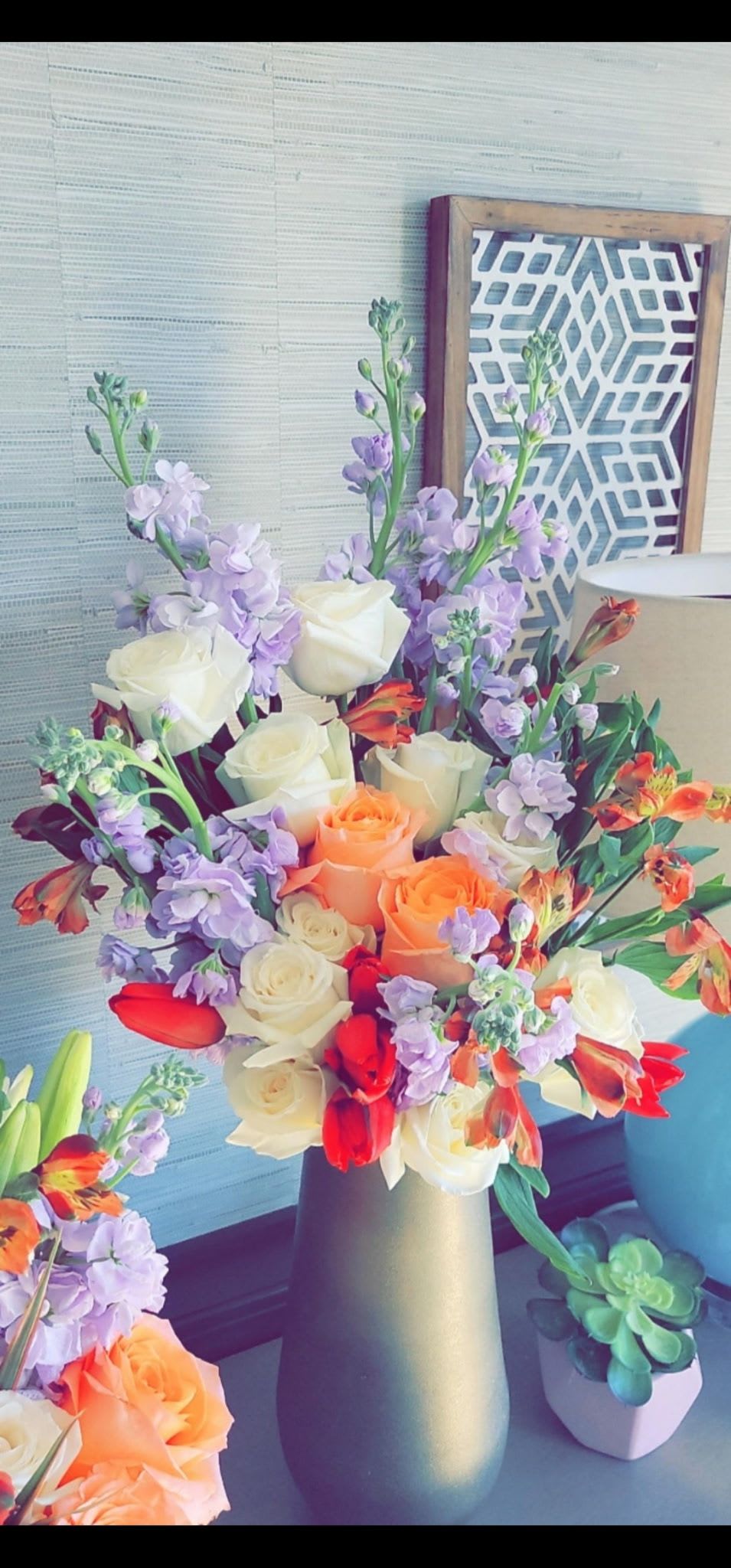 Bouquet of cream, peach, red, and lavender flowers in a matte vase