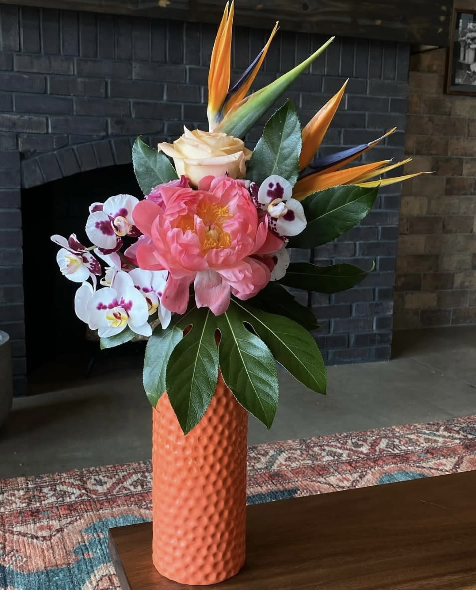 Pink peony and orchids in an orange vase