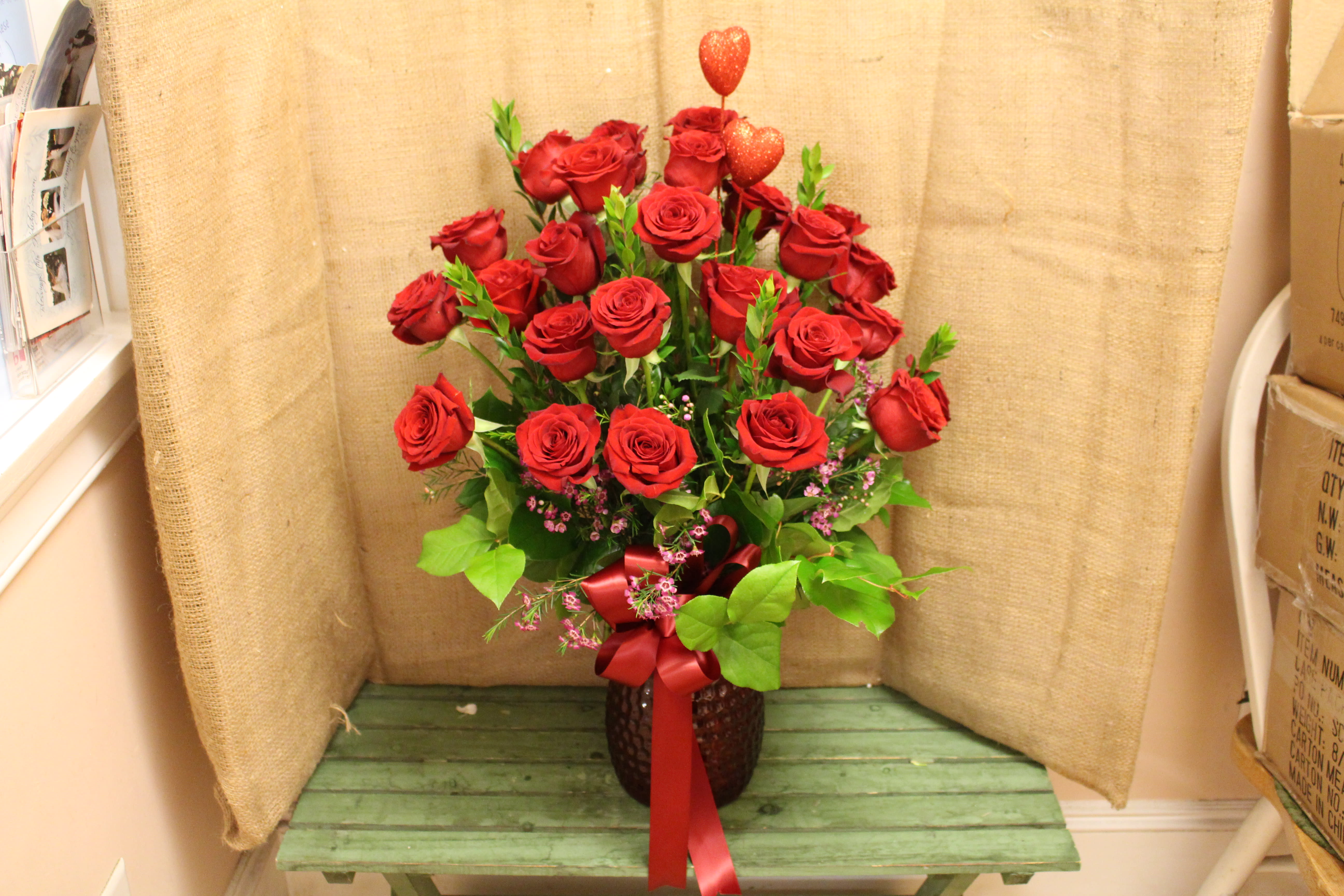 Red roses arranged in a vase with a red ribbon