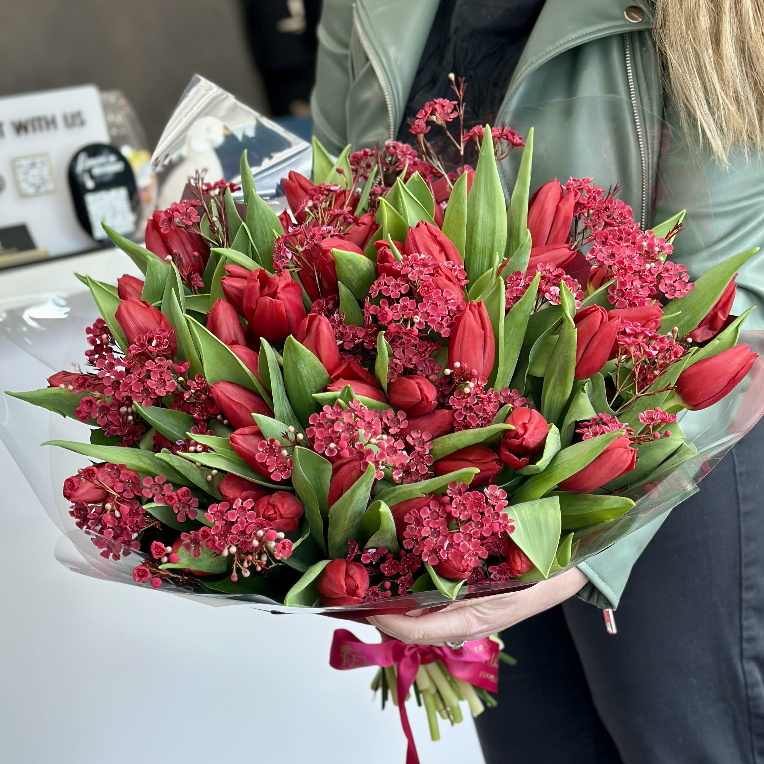 Bouquet of red tulips and pink filler flowers wrapped in clear plastic