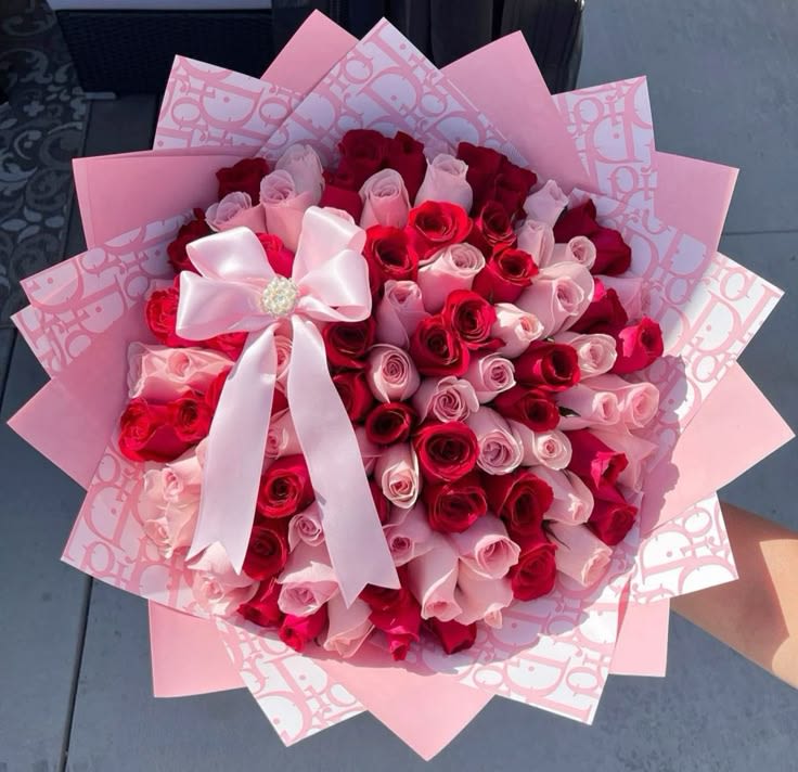 Bouquet of red and pink roses wrapped in pink paper with a white bow