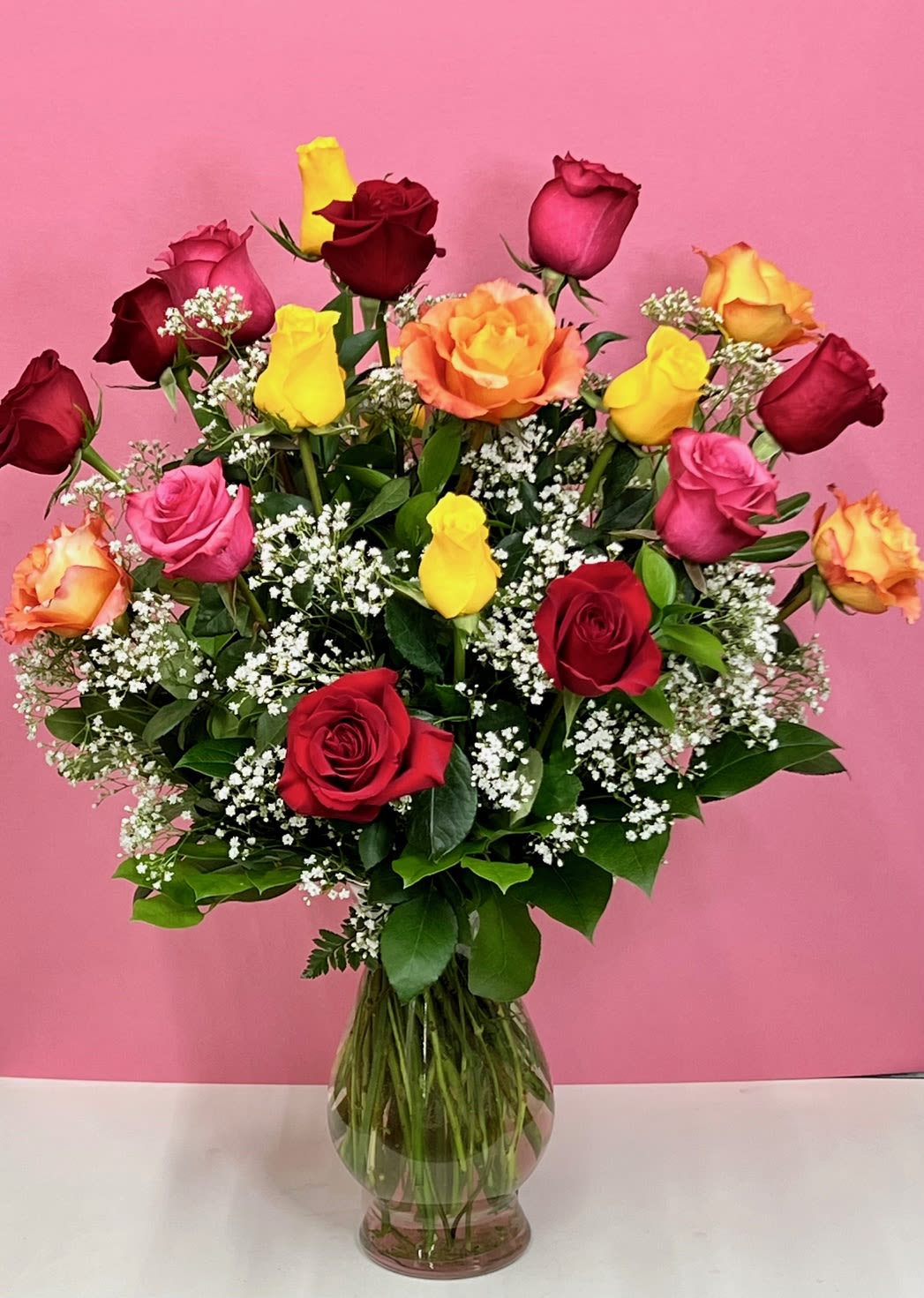 Mixed roses in a clear glass vase with baby's breath