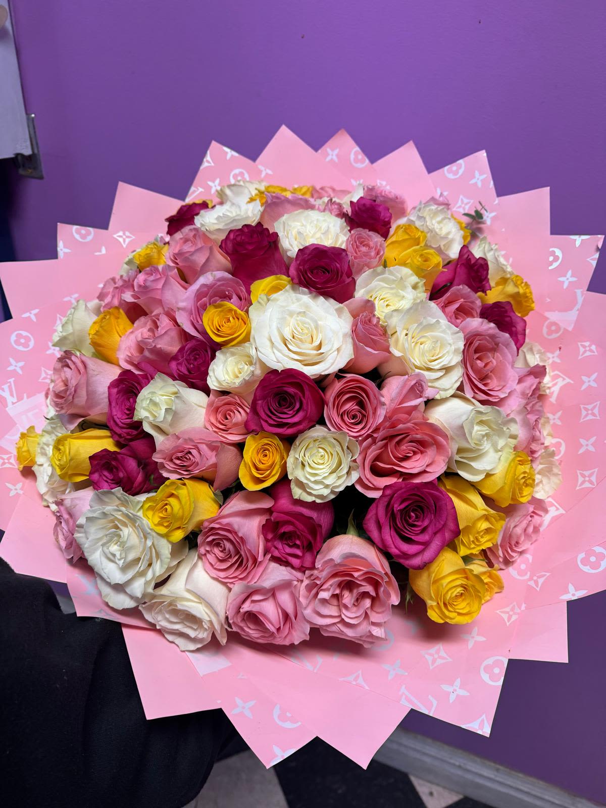 Bouquet of pink, white, and yellow roses wrapped in pink paper