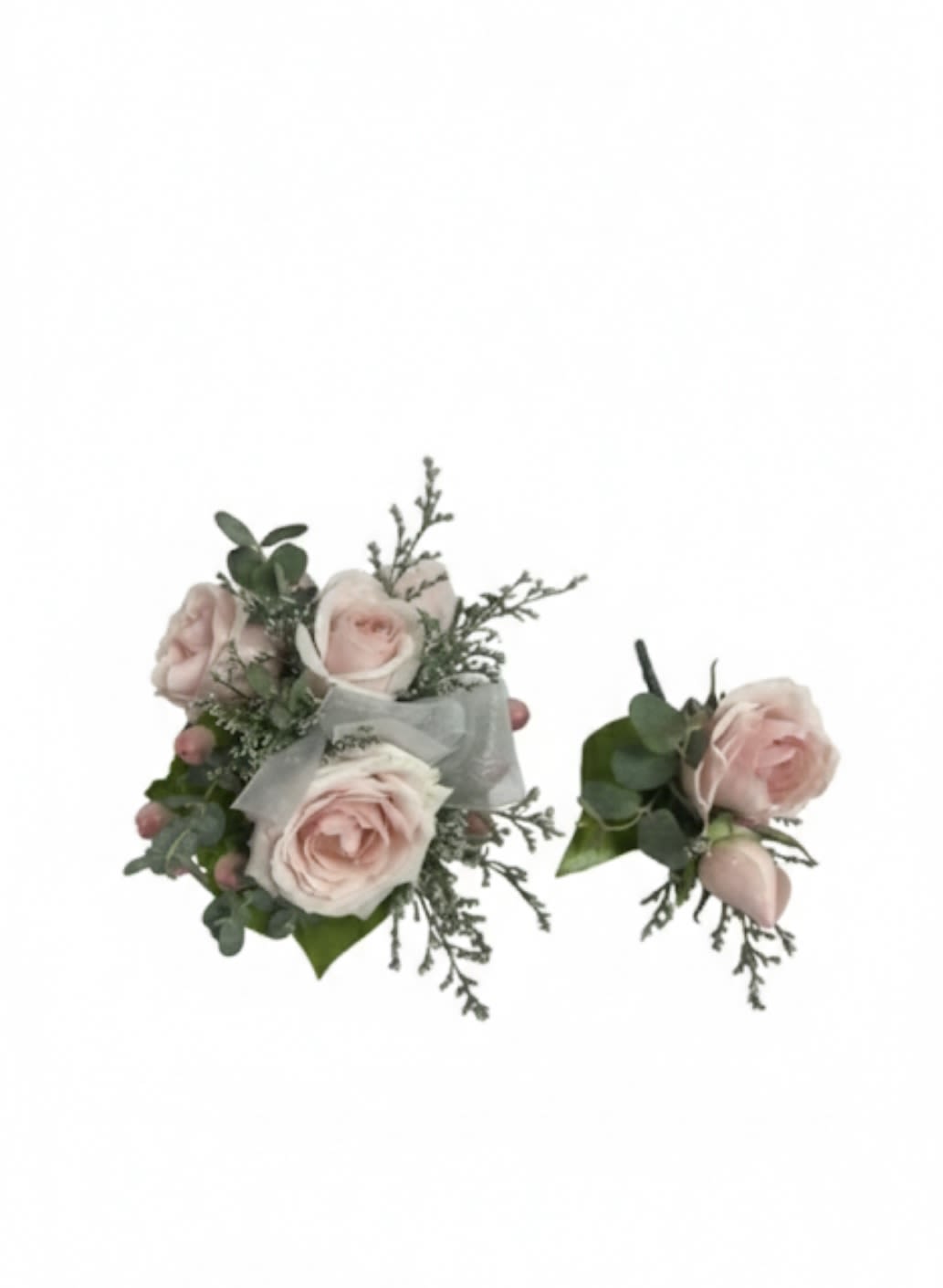 Two pale pink rose boutonnieres with greenery and ribbon