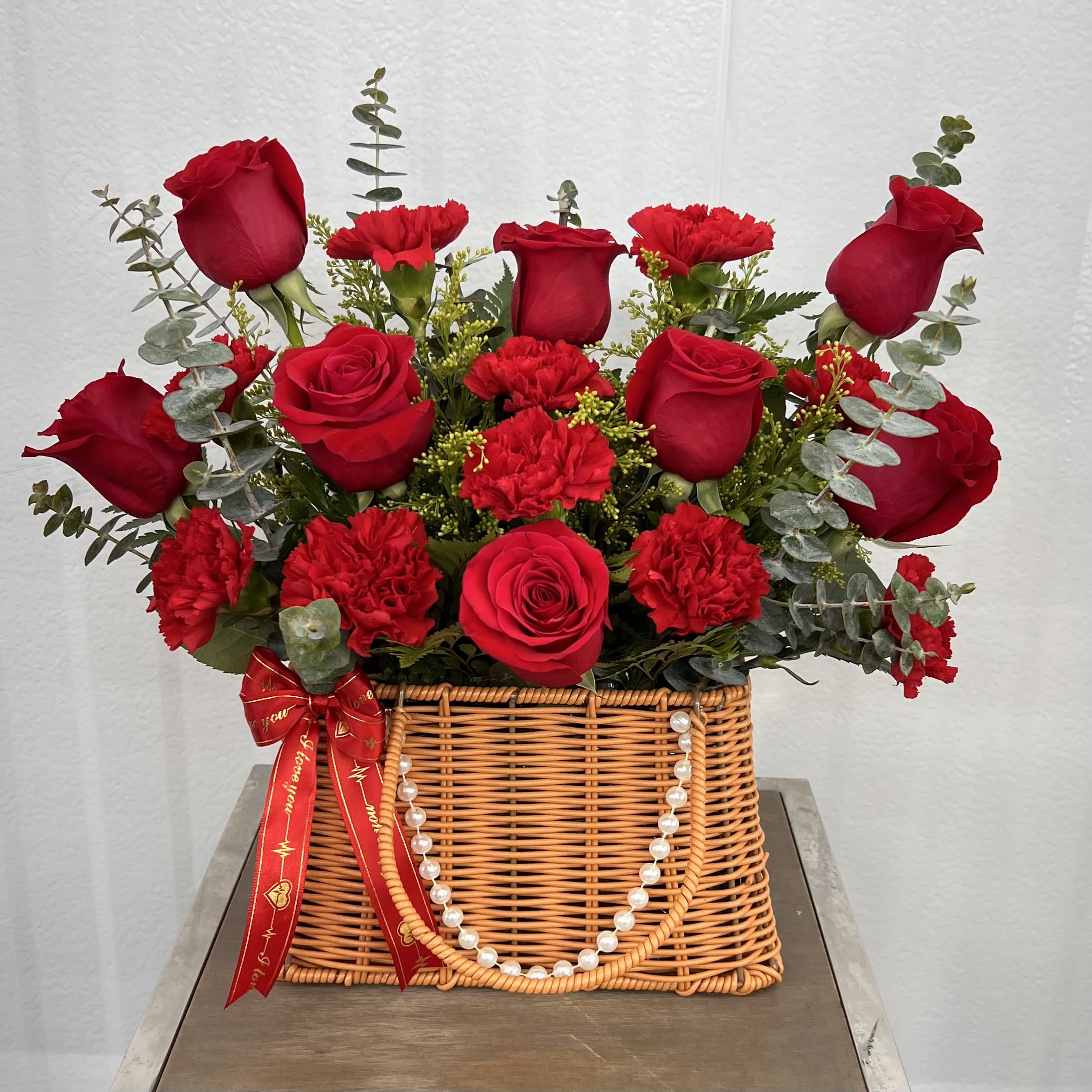Arleth Love Basket - Red Roses And Red Carnations - A charming basket arrangement featuring fresh red roses and carnations, accented with eucalyptus and delicate greenery. Perfect for expressing love, admiration, and heartfelt emotions.