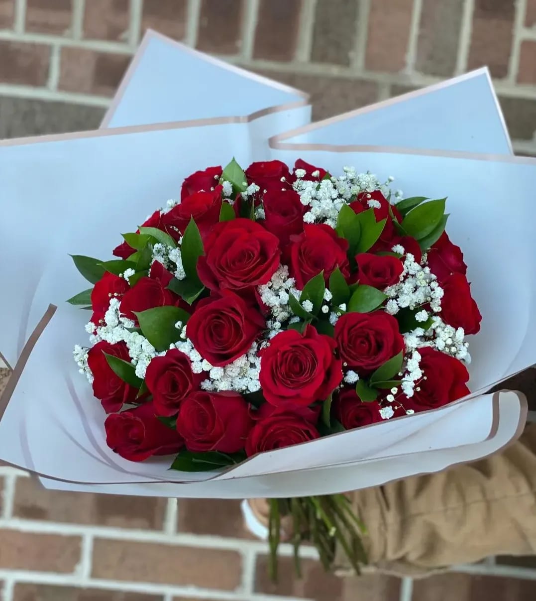 Bouquet of red roses with white baby's breath in white wrapping