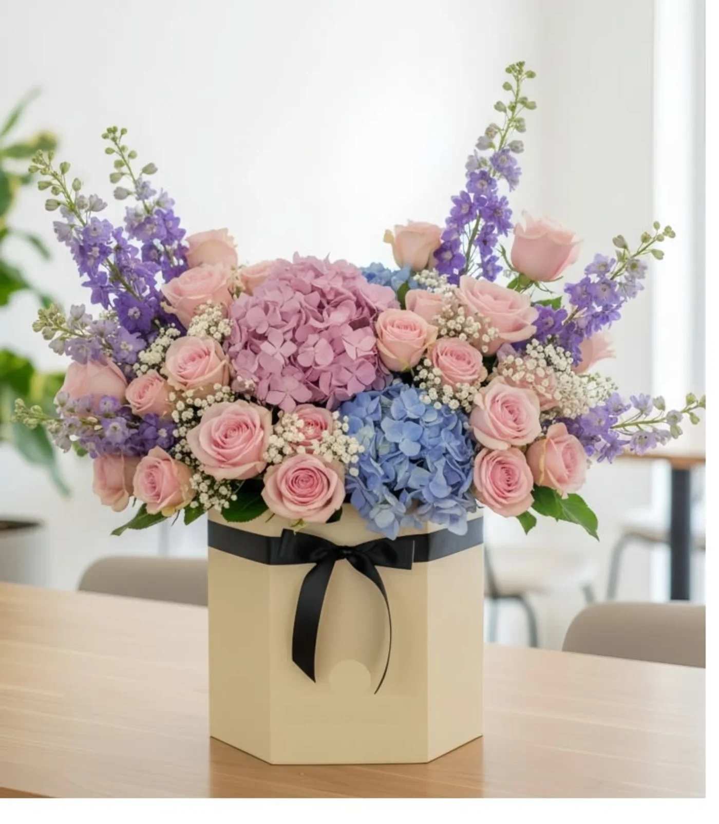 Graceful Harmony round box - This vibrant one-sided arrangement features soft pink hydrangeas, &amp; vibrant blue hydrangeas, elegant spray roses , Pink roses, all beautifully accented with fresh Stock .green fillers and round box,this bouquet brings a burst of warm colors, making it a perfect choice to express love, admiration, and joy.