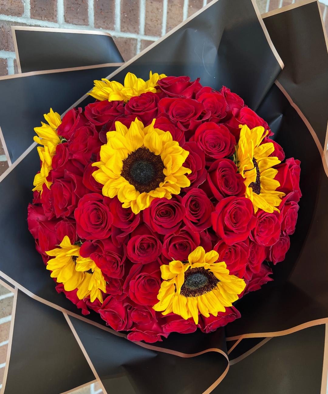 Bouquet of red roses with yellow sunflowers wrapped in black paper