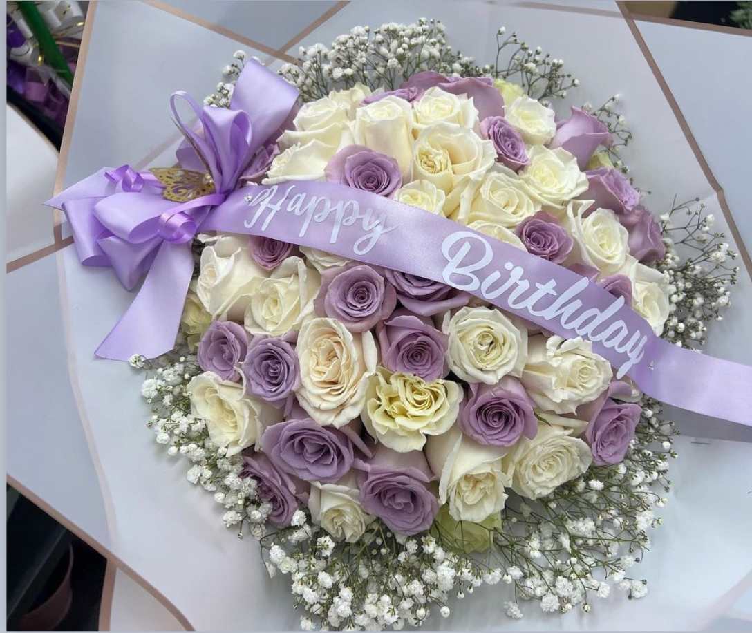 Bouquet of cream and lavender roses with a birthday ribbon